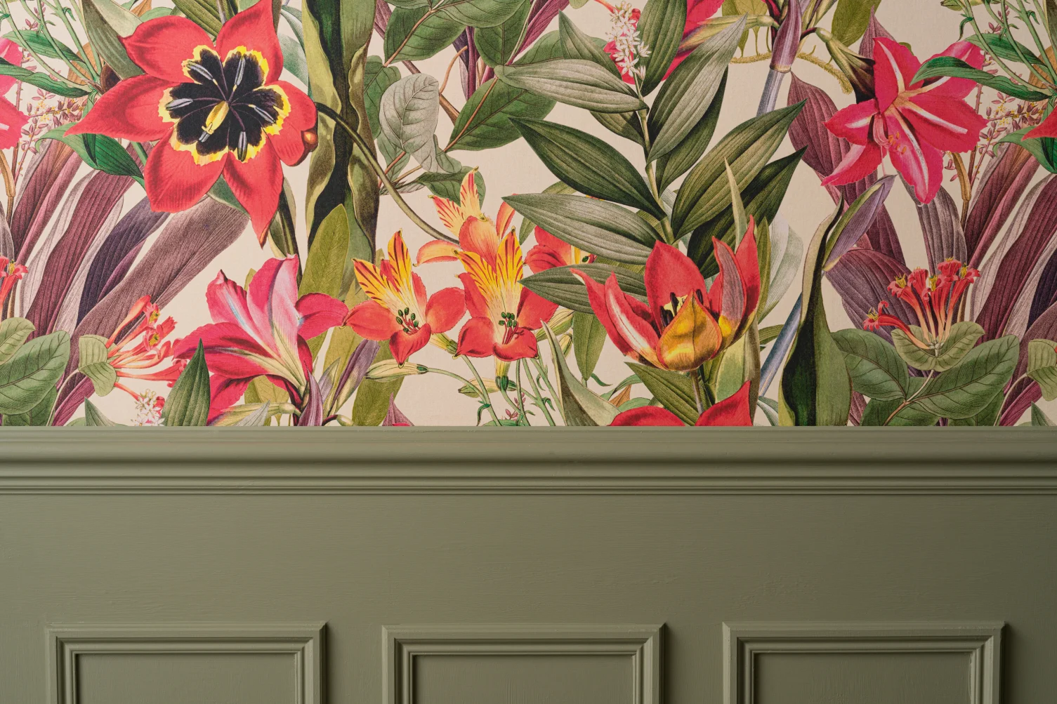 A newly hung vibrant tropical floral wallpaper with red, yellow, and green hues against a wall with sage green paneling.