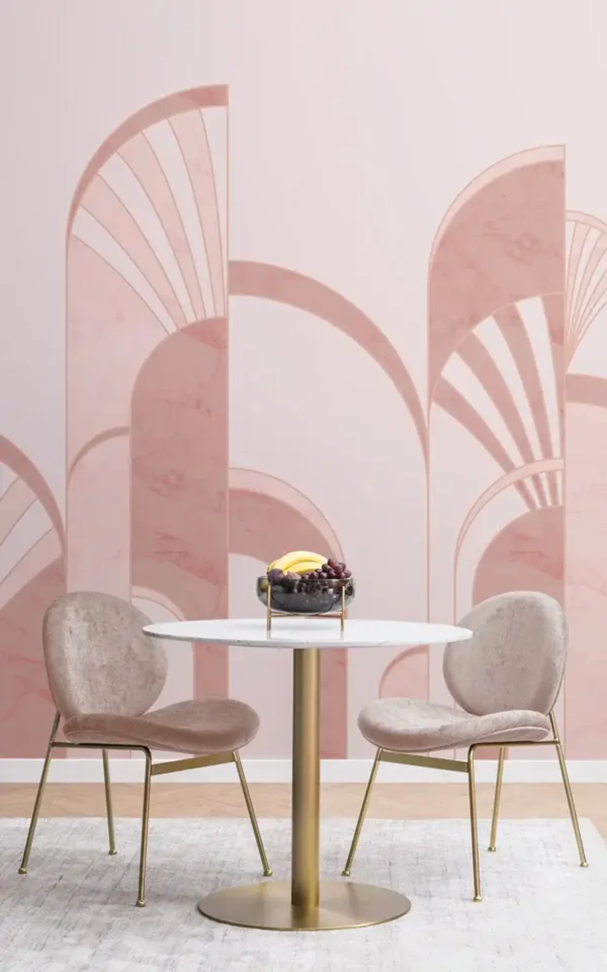 A chic dining area with two plush, velvet chairs in light taupe beside a white marble tabletop on a gold pedestal base, set against a soft pink backdrop with Art Deco-style arch motifs.