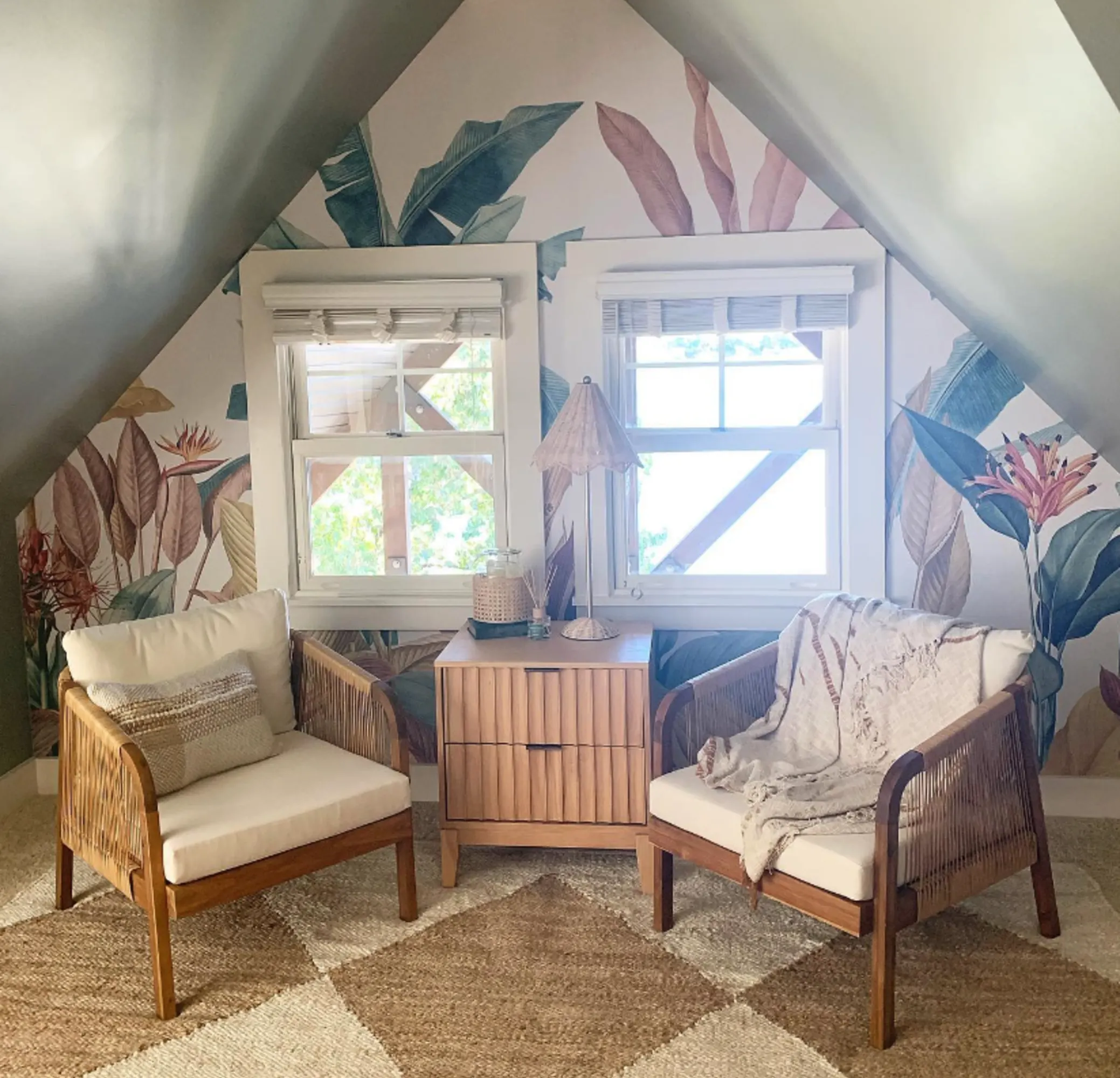 A cozy attic nook with a tropical botanical mural, a rattan lounge set, and natural decor elements.