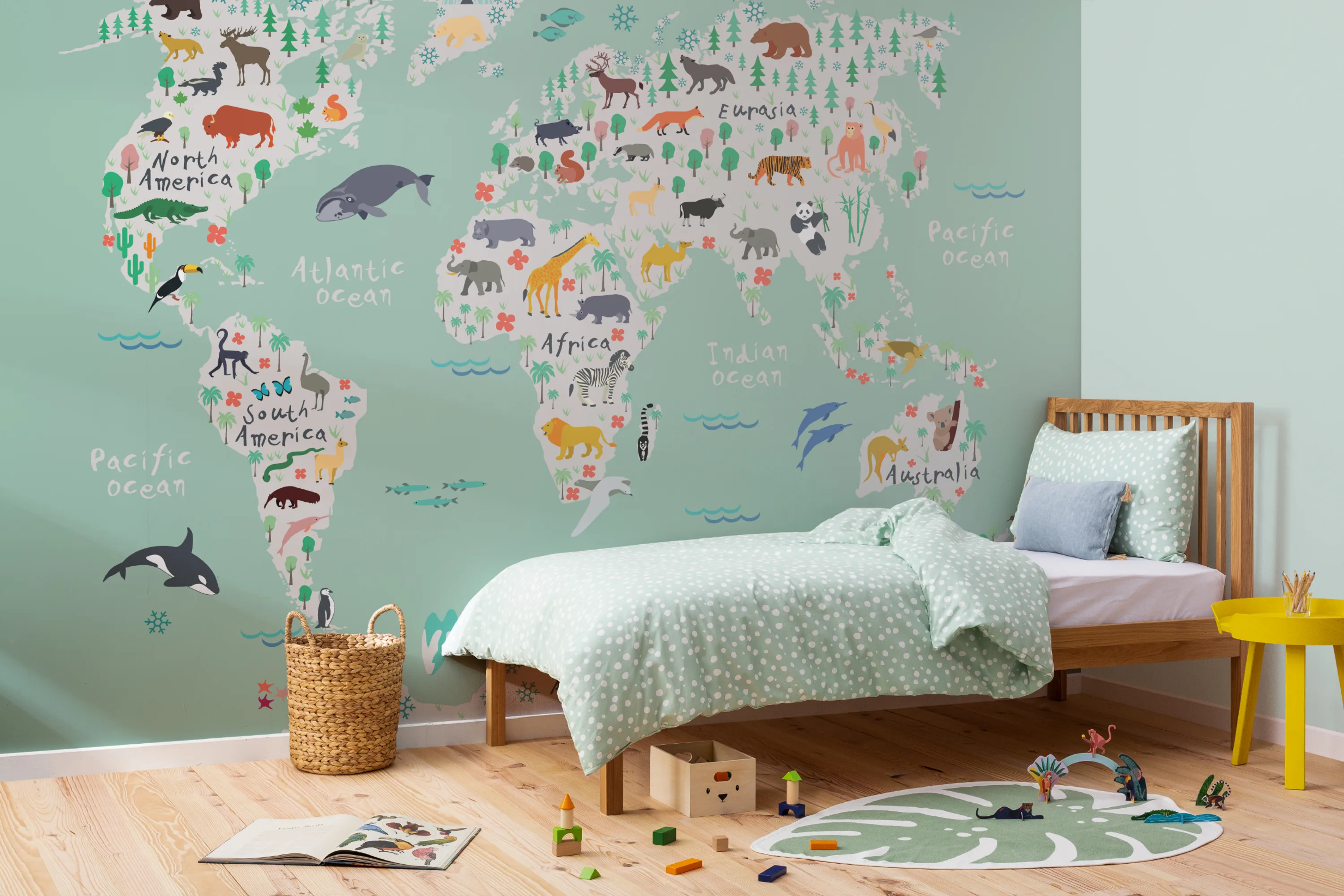 A playful world map mural featuring animals and continents, adorning a child’s bedroom wall with a wooden bed and green bedding.