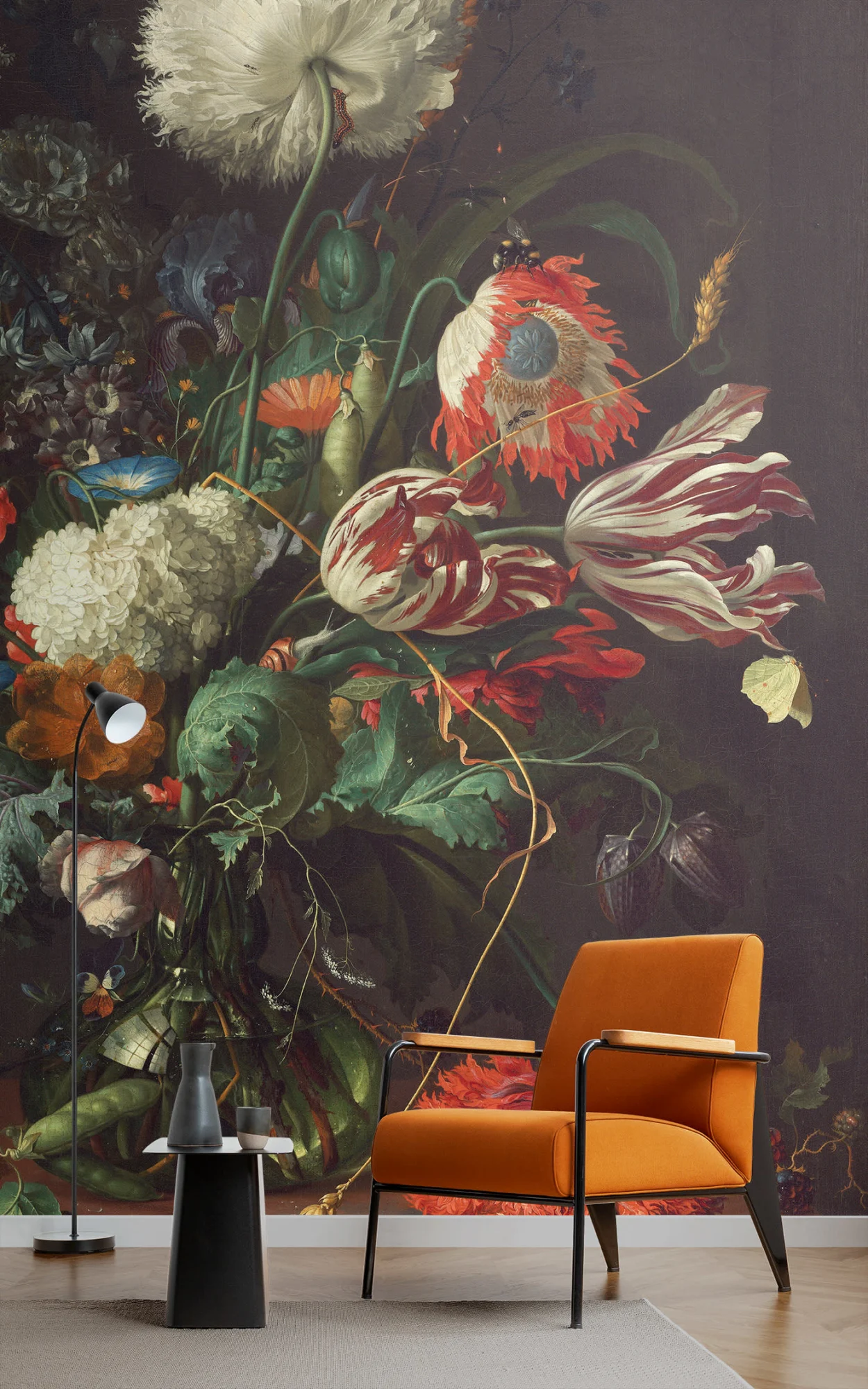 Modern interior with a vibrant floral wall mural featuring large, detailed flowers. Includes a minimalist orange armchair, a small black side table with a lamp, and a simple grey floor rug.
