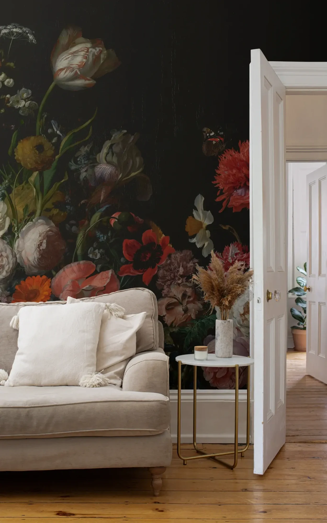  A cozy living room space featuring an opulent, dark floral wallpaper filled with vivid, large blooms. 