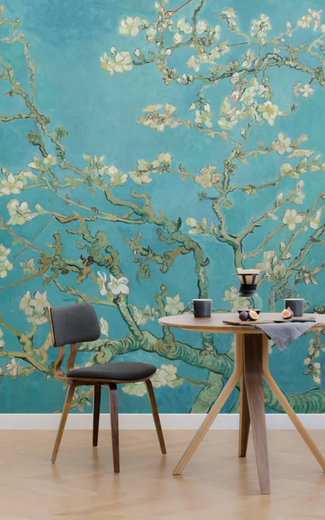 An elegant dining area featuring a wooden table with modern chairs, set against a stunning mural inspired by Van Gogh's "Almond Blossoms" in vibrant turquoise and soft green hues, which adds a touch of artistic flair to the room.