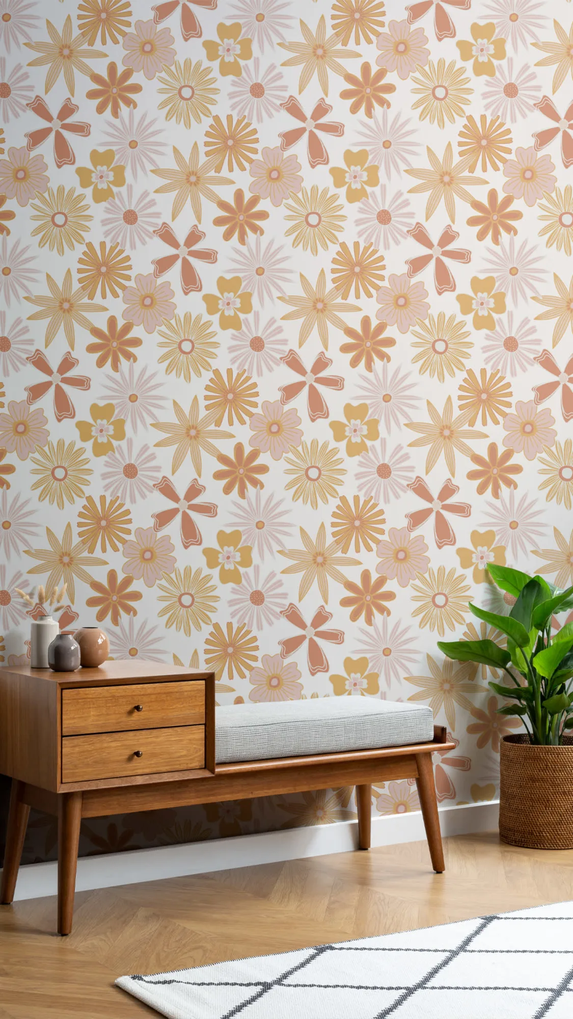  A bright and airy corner of a room featuring a mid-century modern wooden bench with a gray cushion against a vibrant floral wallpaper in shades of yellow, orange, and pink, complemented by a woven basket with a lush green plant and a simple white and black geometric rug on a light wooden floor.