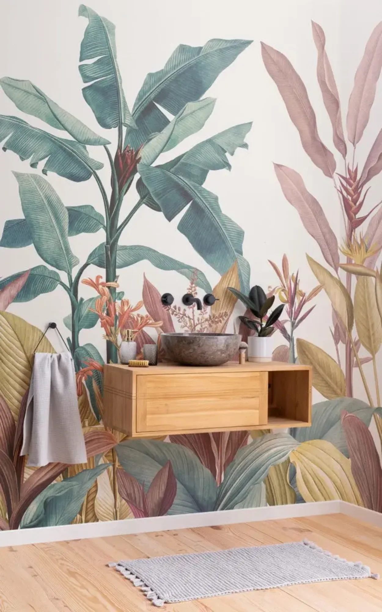  The bathroom features a tropical-themed wallpaper with oversized botanical prints in soft pastel tones, complemented by a sleek wooden vanity that enhances the naturalistic and serene ambiance.
