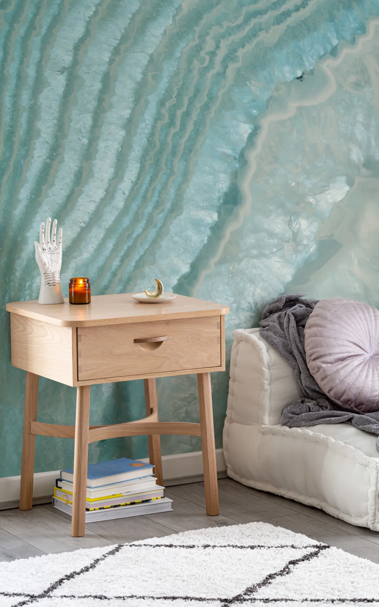 Cozy corner with wooden side table, crystal effect wall mural, white shag rug, and plush cushions.