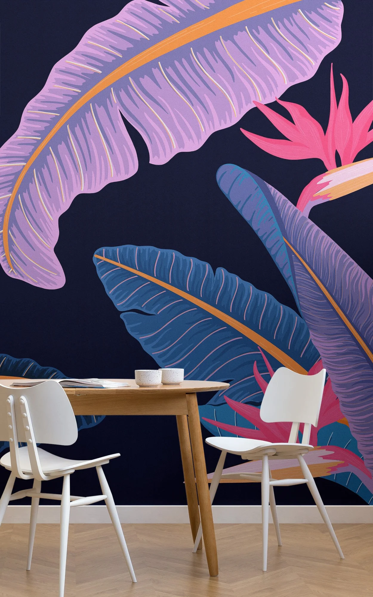 A vibrant dining area with a wooden table and white chairs against a dark blue wall adorned with large, colorful tropical leaf and bird motifs.