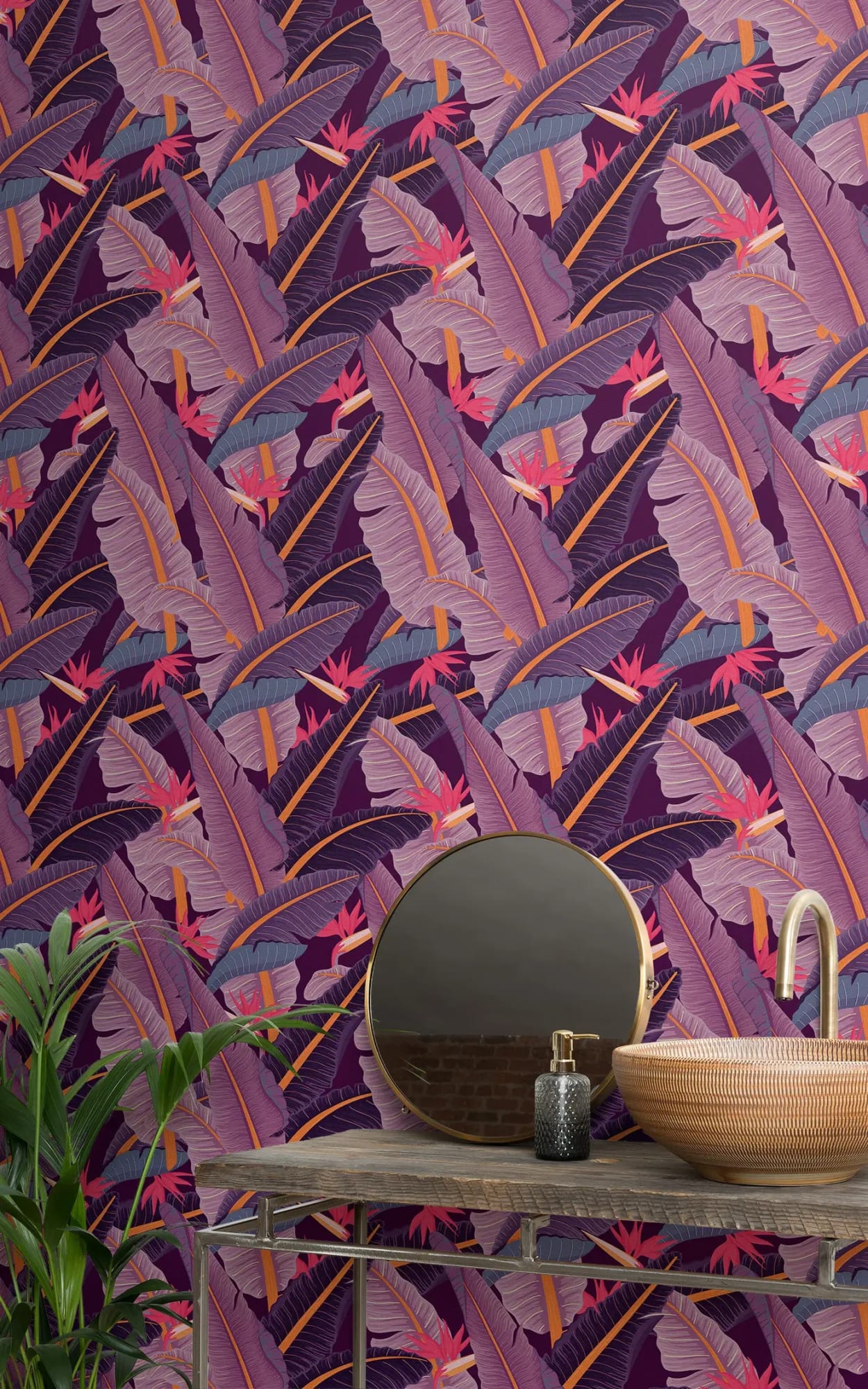A chic bathroom setting with a rustic vanity table and round mirror against a vibrant purple wallpaper adorned with tropical leaf and bird motifs in shades of purple and pink.