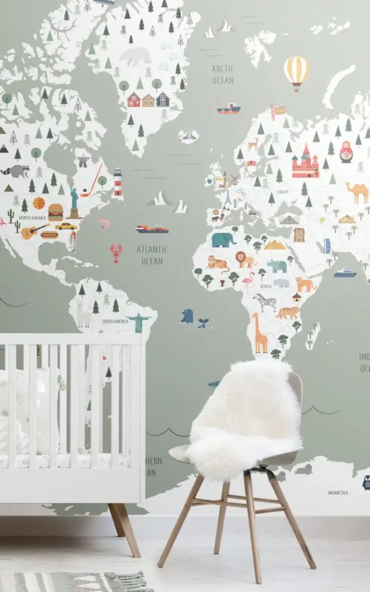  A children's room features a world map mural with illustrations of animals and landmarks, a white crib, and a chair with a white fur throw.