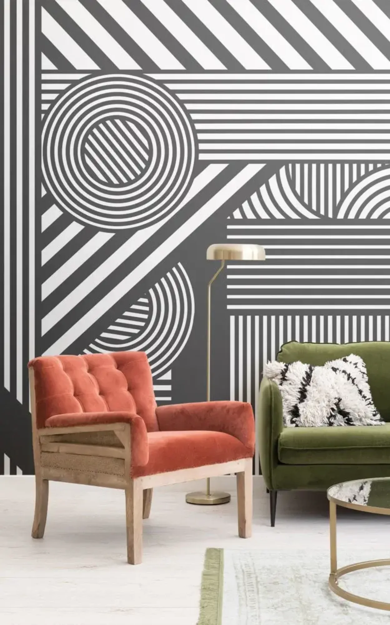 A modern living room features a green sofa with patterned cushions, an orange tufted armchair, a gold floor lamp, and a bold black-and-white geometric patterned wall.