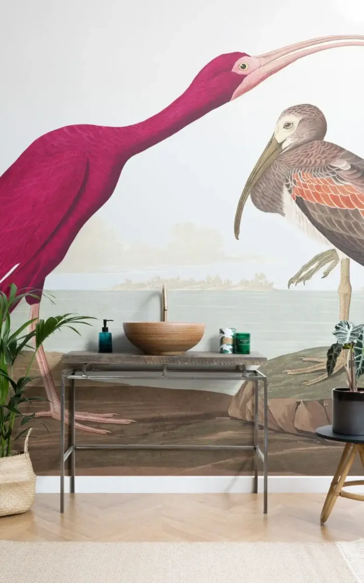 A bathroom features a scenic mural of two large ibises, a wooden vessel sink on a metal console table, and potted plants for decor.