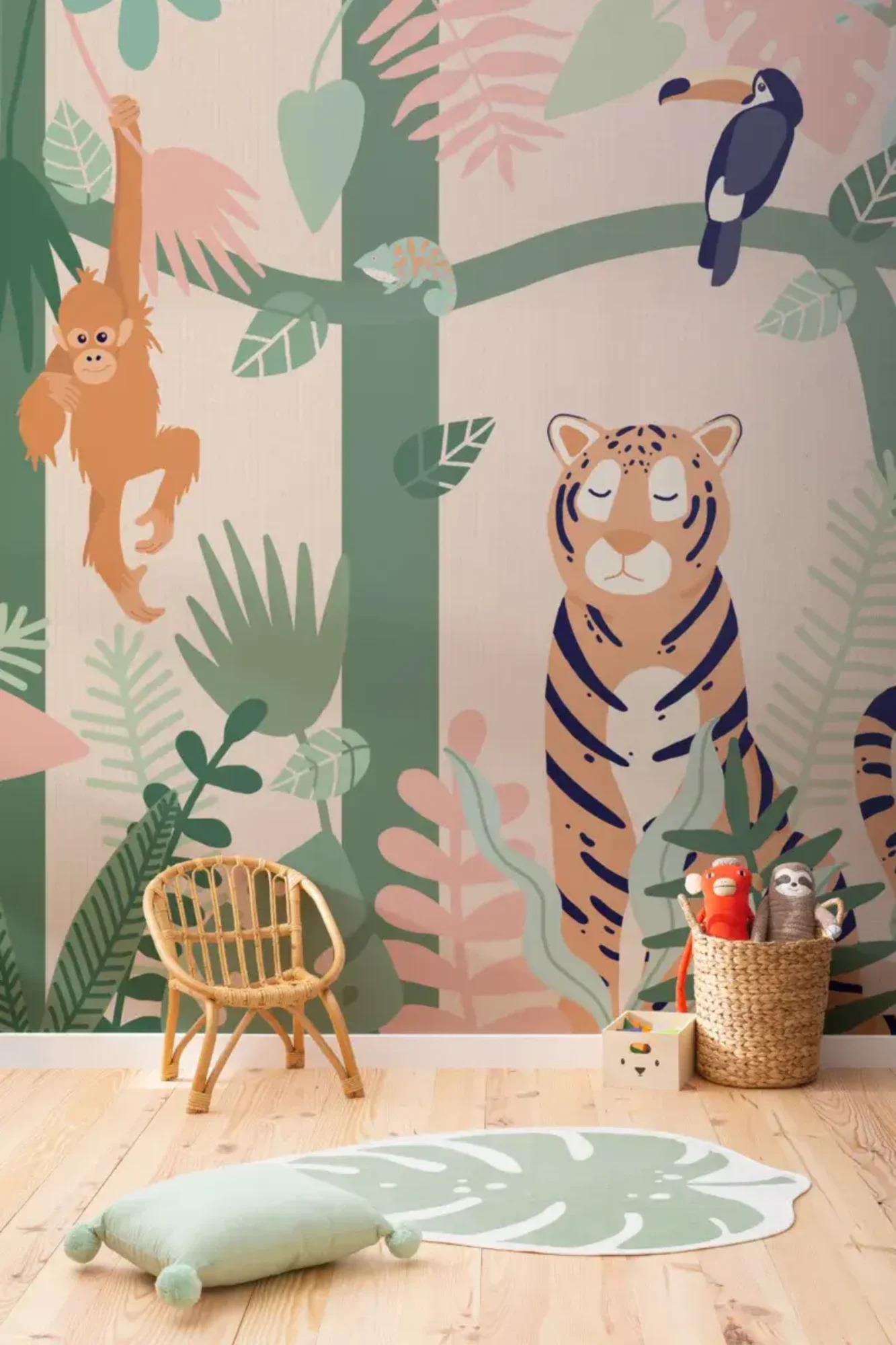 A colorful jungle-themed wallpaper featuring a tiger, toucan, orangutan, and various plants decorates a child's room with a wicker chair, a green leaf-shaped pillow, and a basket of plush toys.
