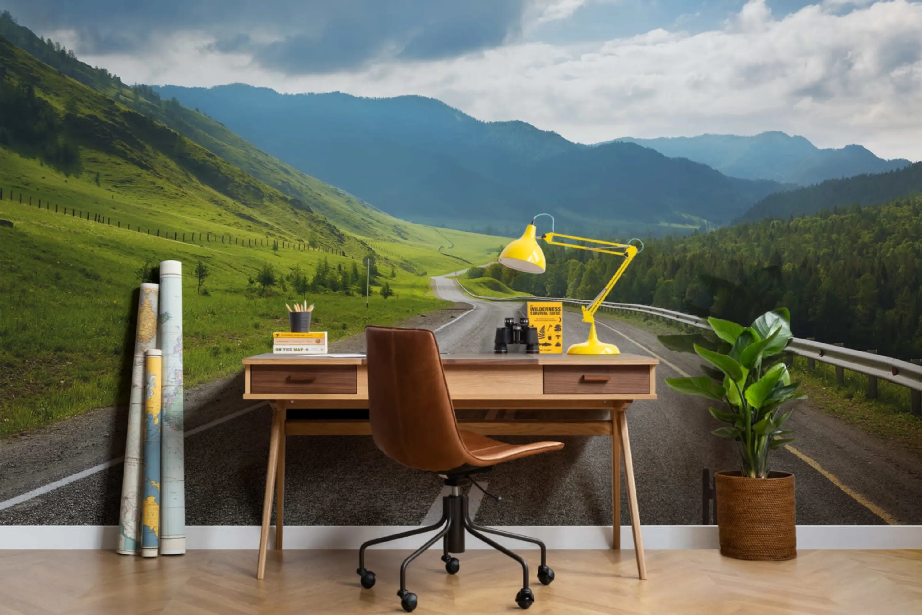 A study area featuring a wooden desk with a yellow lamp, a brown chair, and a background mural of a winding road through green hills and mountains under a partly cloudy sky.