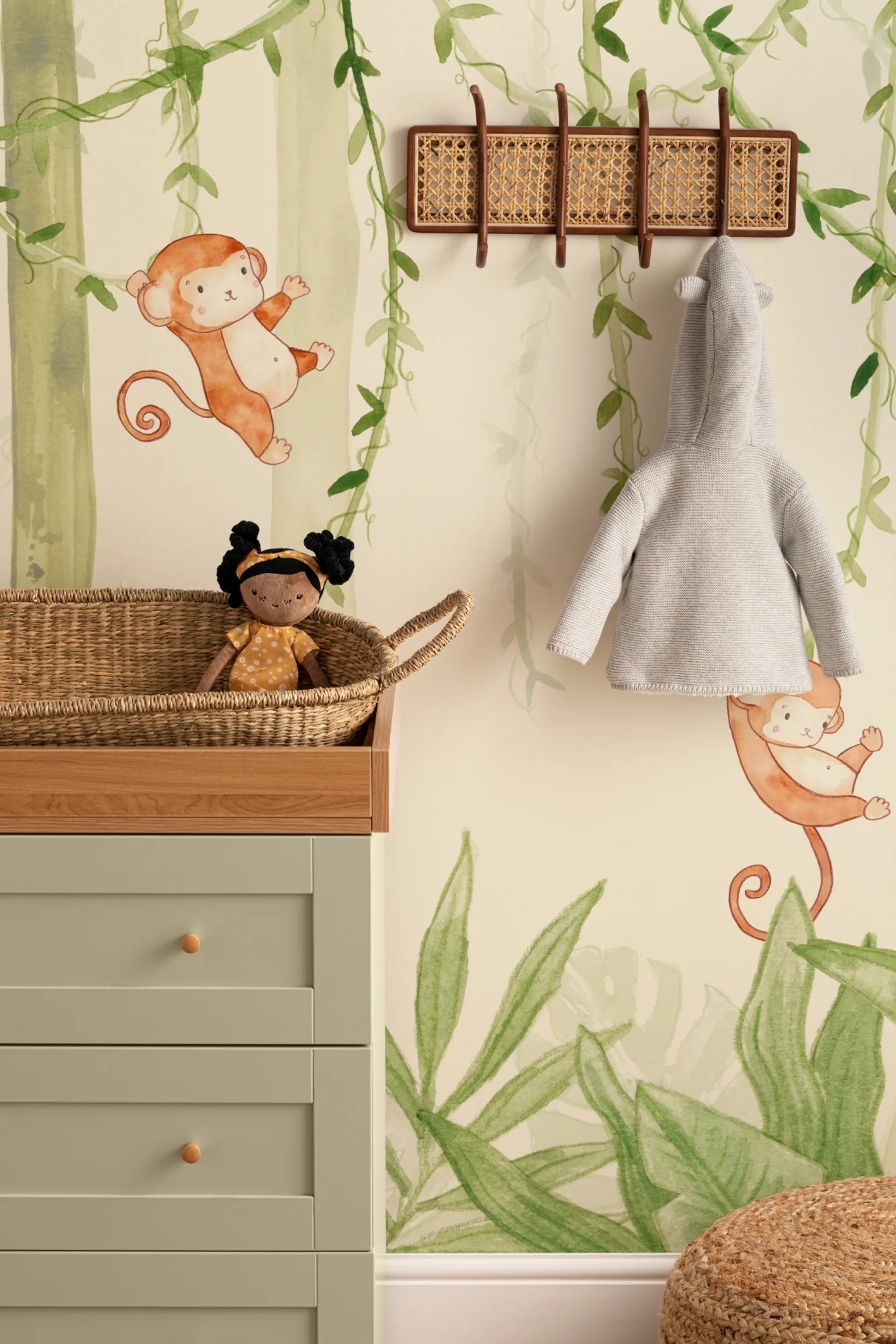 A nursery with a jungle-themed mural showing playful monkeys hanging from vines.