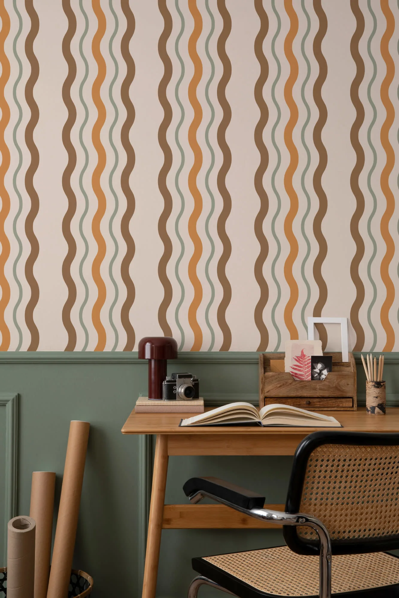 A retro-inspired office with wavy striped wallpaper in earthy tones, a wooden desk, and a cane-back chair.