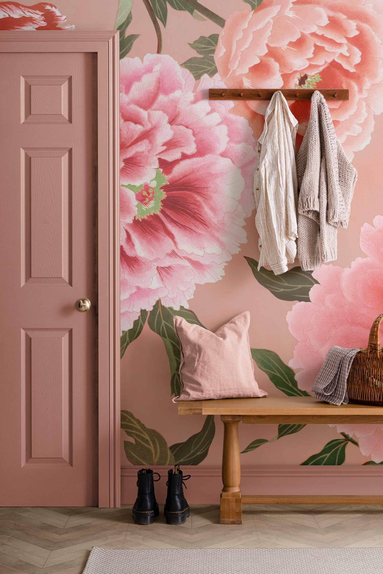A charming hallway with oversized pink peony floral wallpaper, a wooden bench, and soft fabric accents.