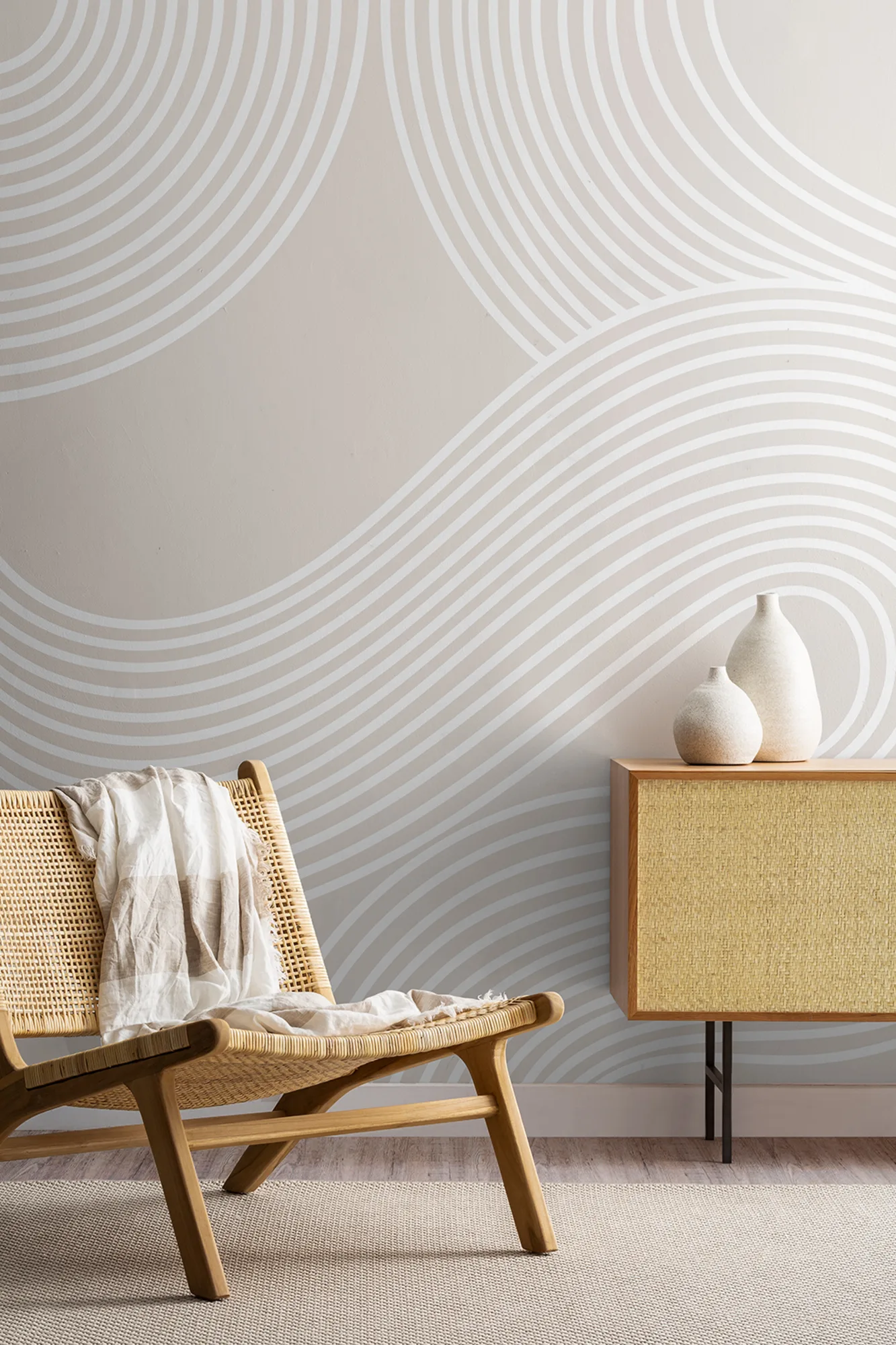 A minimalist living space featuring a wall mural of Zen garden style white wavy lines, paired with rattan furniture and natural accents for a calming atmosphere.