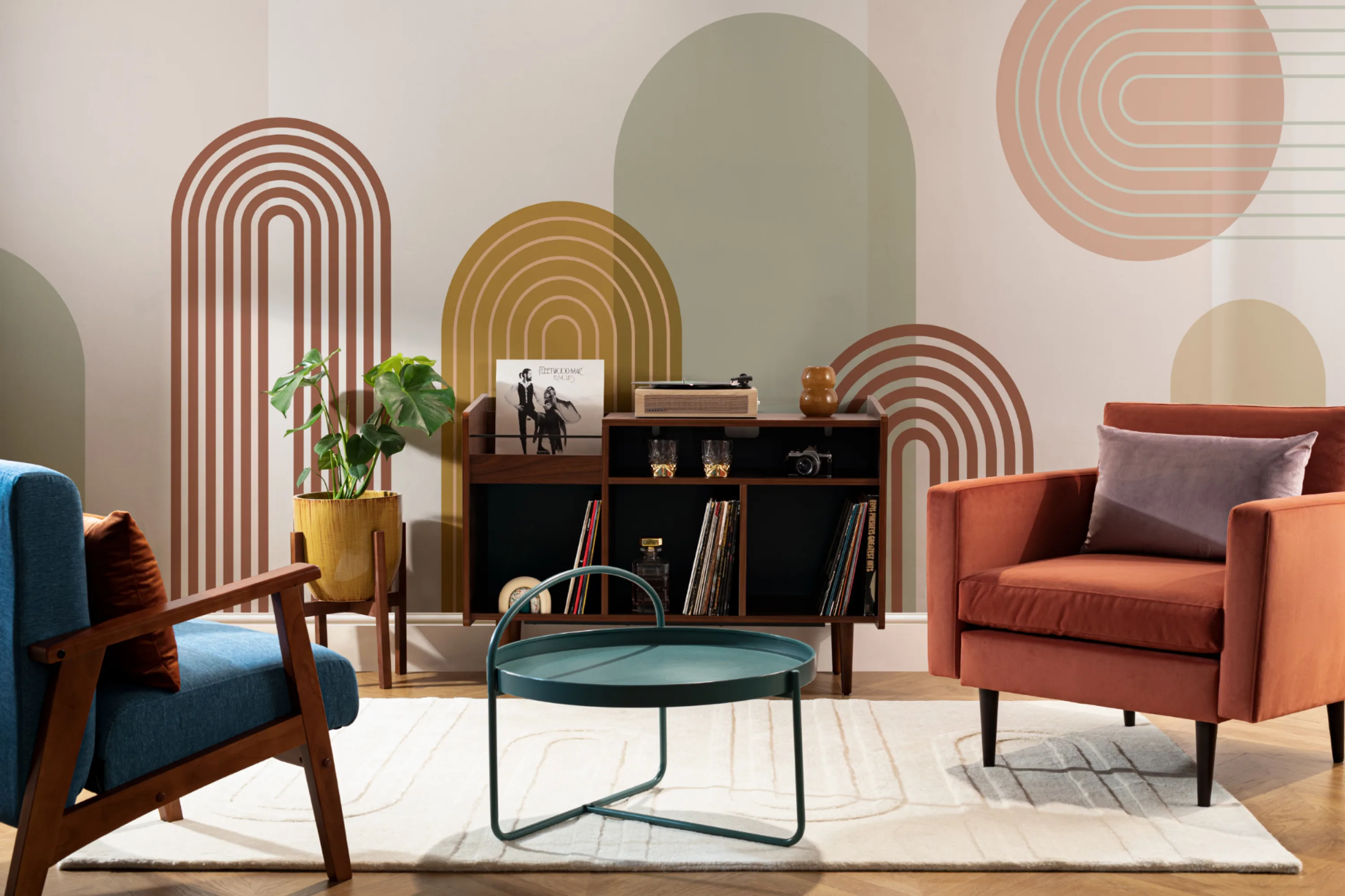 A vibrant Mid-Century modern style living room with geometric arch wallpaper, colorful armchairs, and a sleek wooden media console.