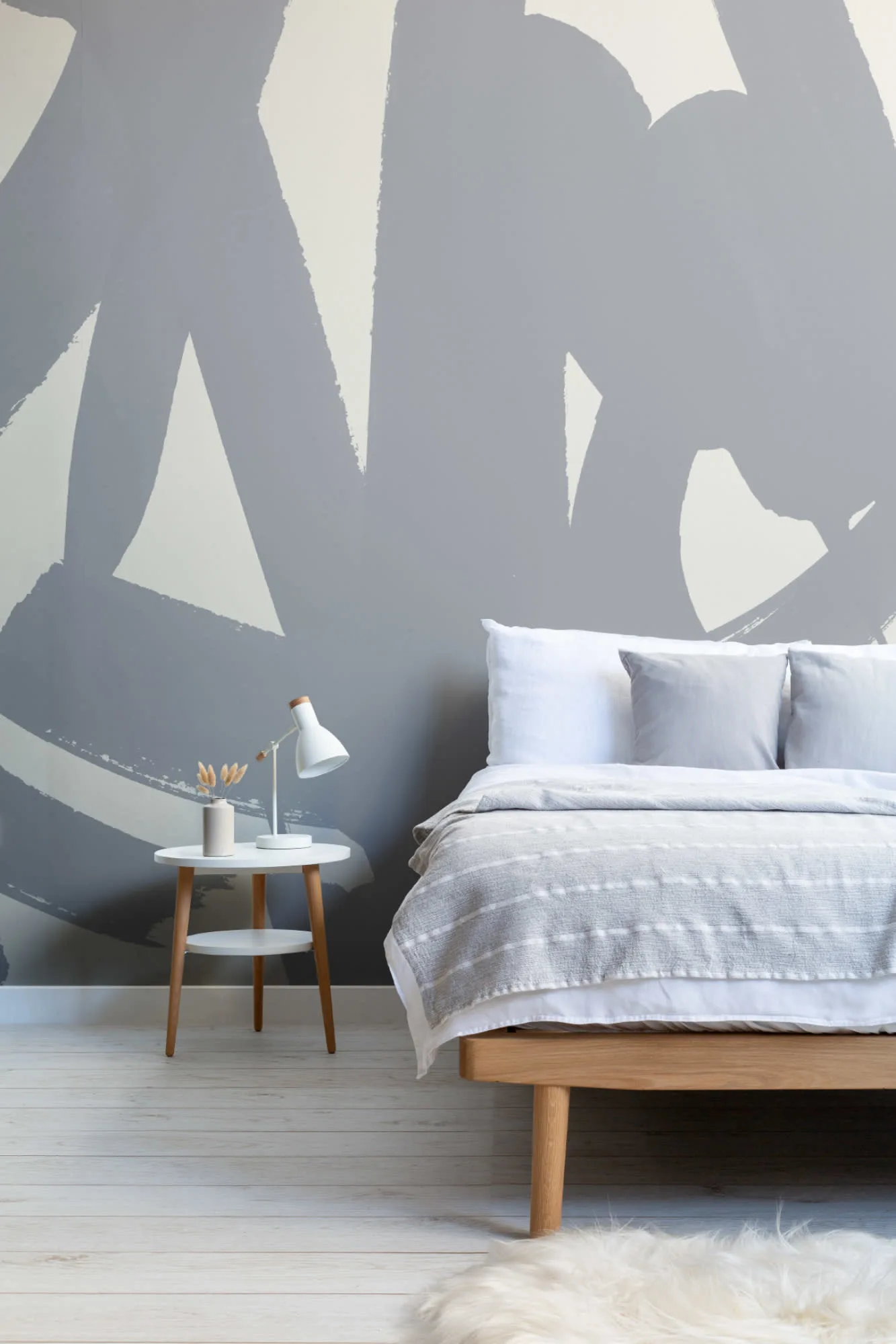 A serene Japandi style bedroom with a gray brushstroke mural, minimal decor, and soft linen bedding.