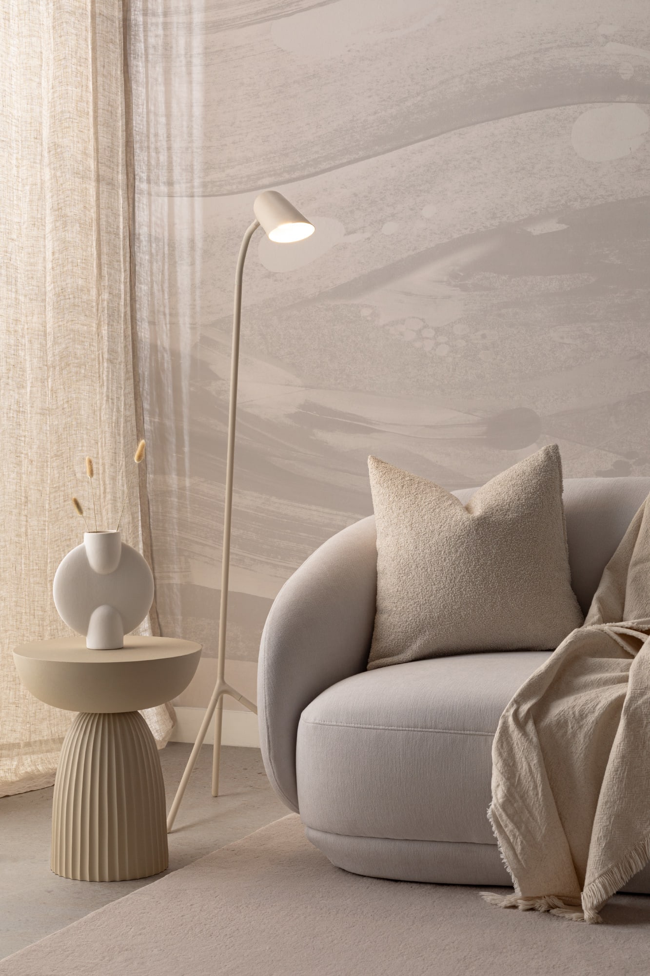 A relaxing Japandi style nook with a cream abstract wall mural, a curved armchair, and textured neutral decor.