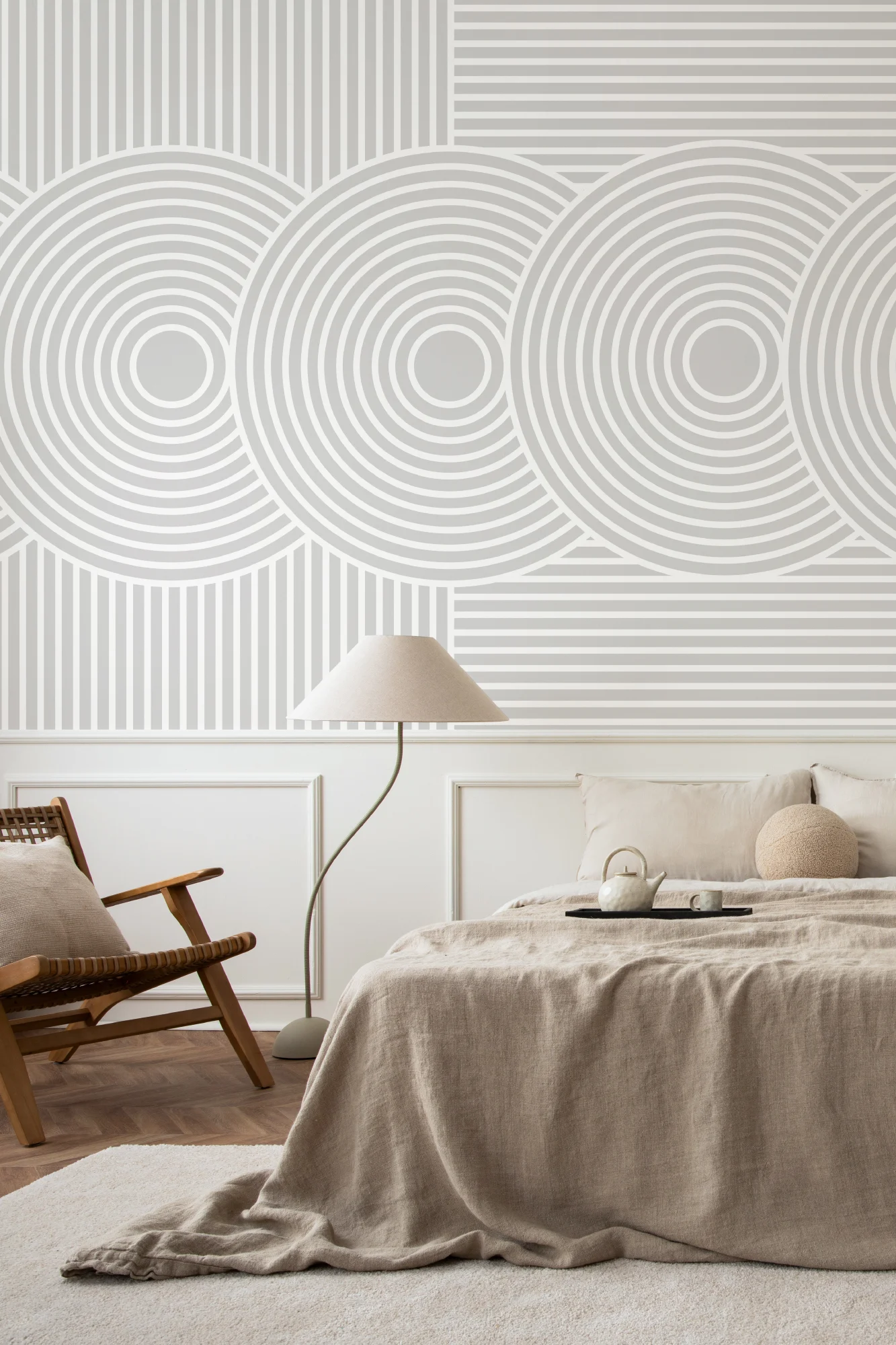 A neutral bedroom with circular Japandi style geometric wall mural, natural linens, and a wooden armchair.
