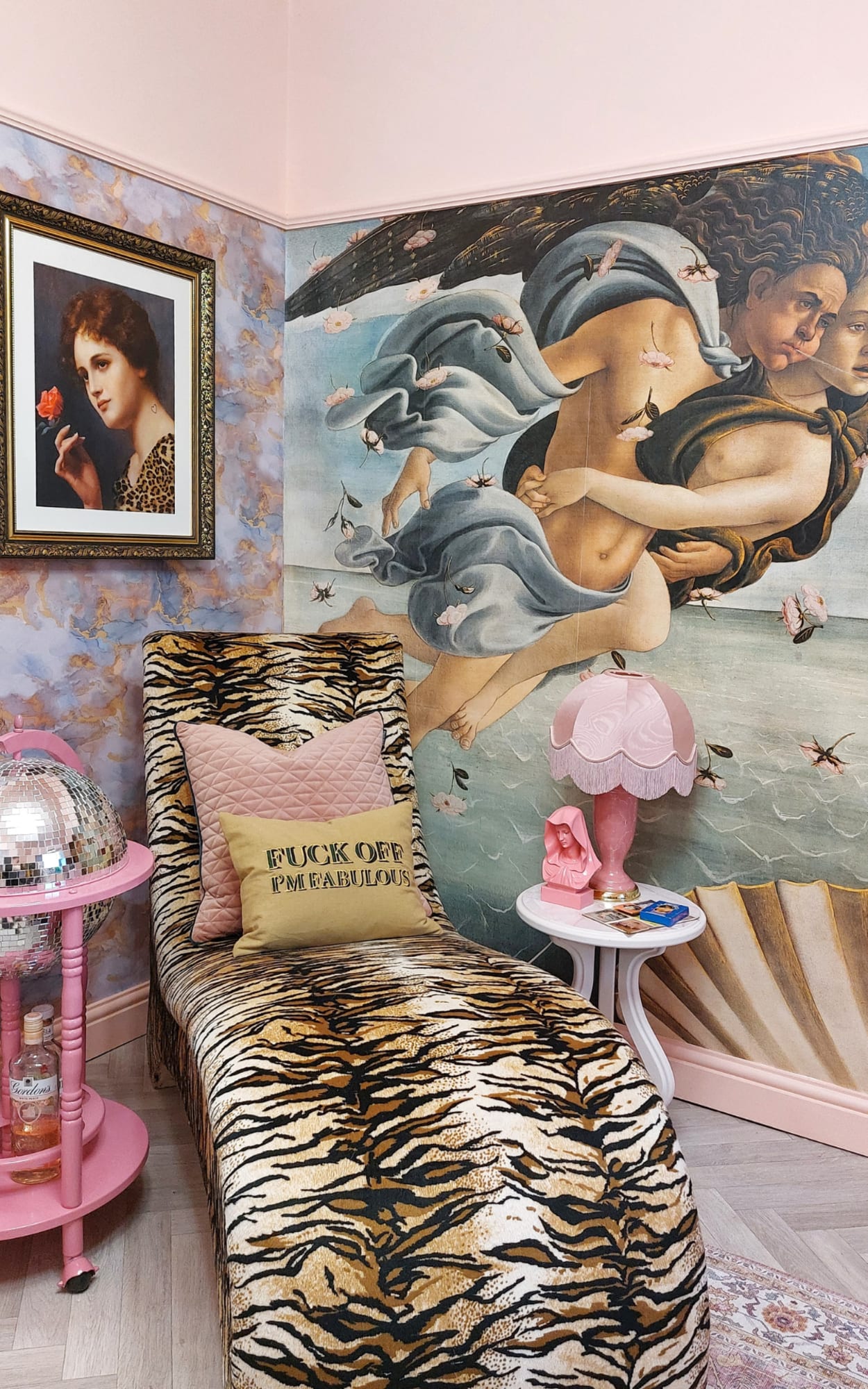 A maximalist bedroom corner featuring a bold Renaissance-inspired wall mural, a tiger-print chaise lounge, and pink decor accents.