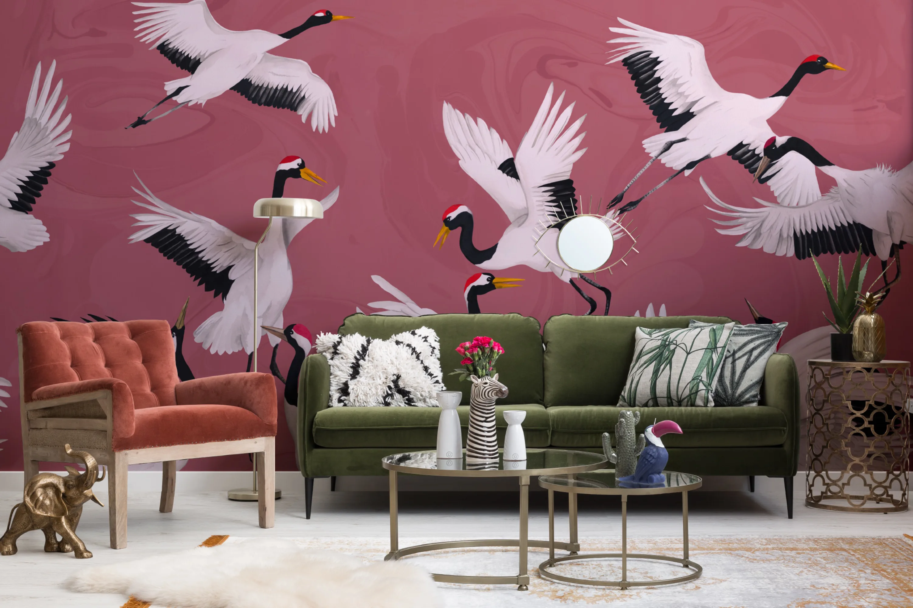 A bold pink mural featuring illustrated cranes in a colorful living room with a green sofa and vintage decor.