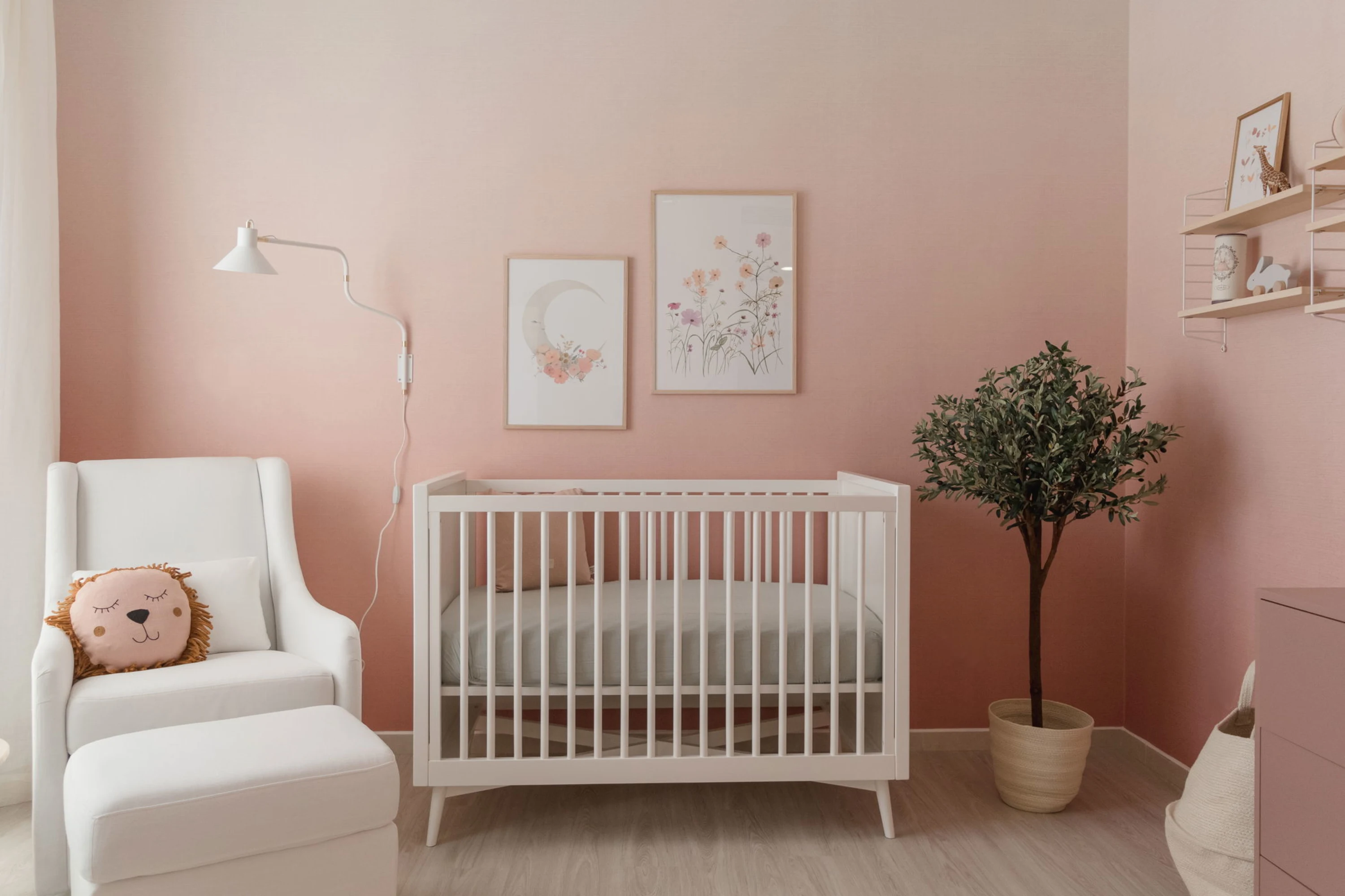 A dreamy nursery with a soft pink ombre wall, a white crib, and framed floral artwork.