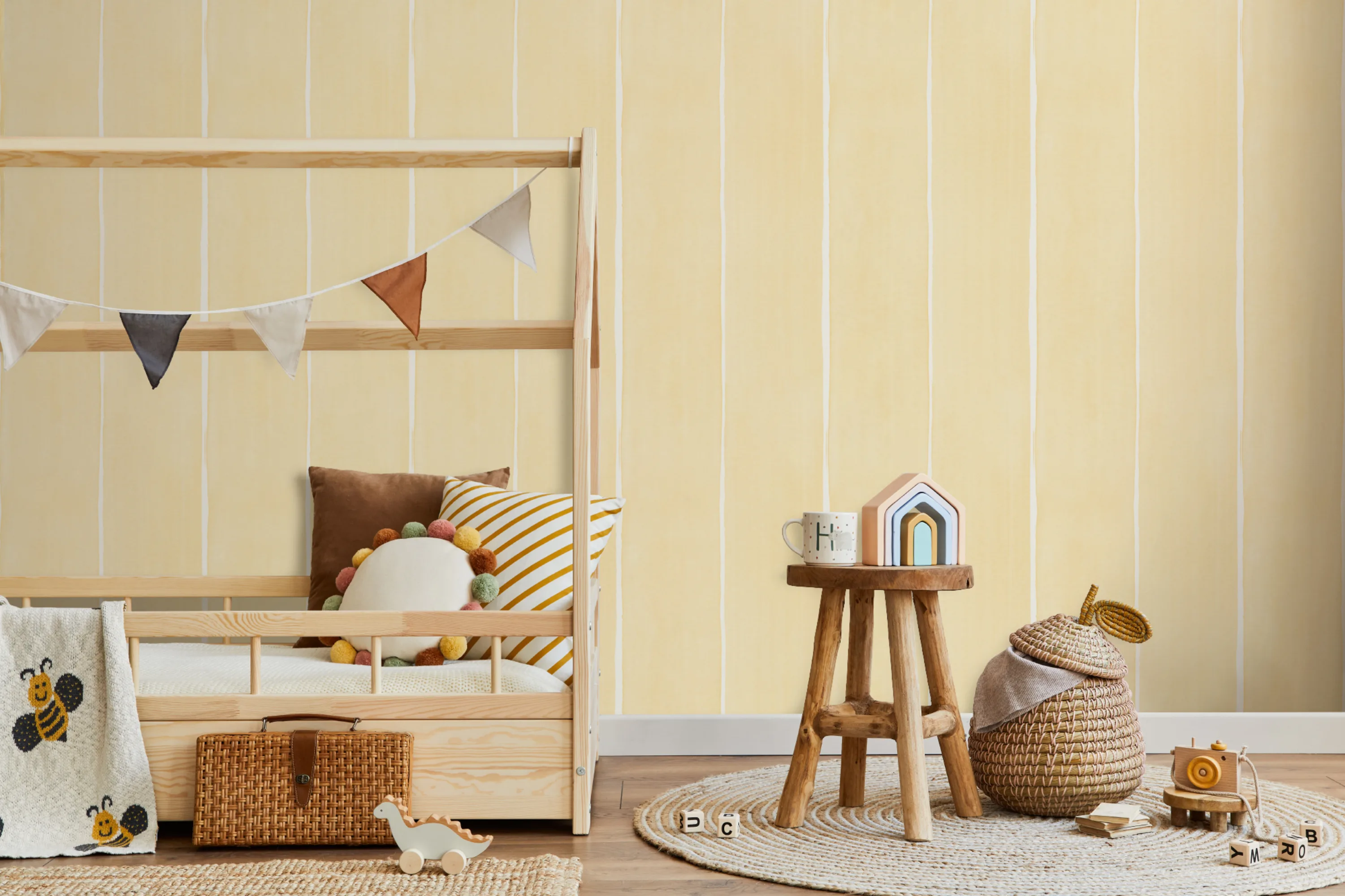 A bright and playful kids' room with soft yellow striped wallpaper, a wooden house-frame bed, and natural decor.