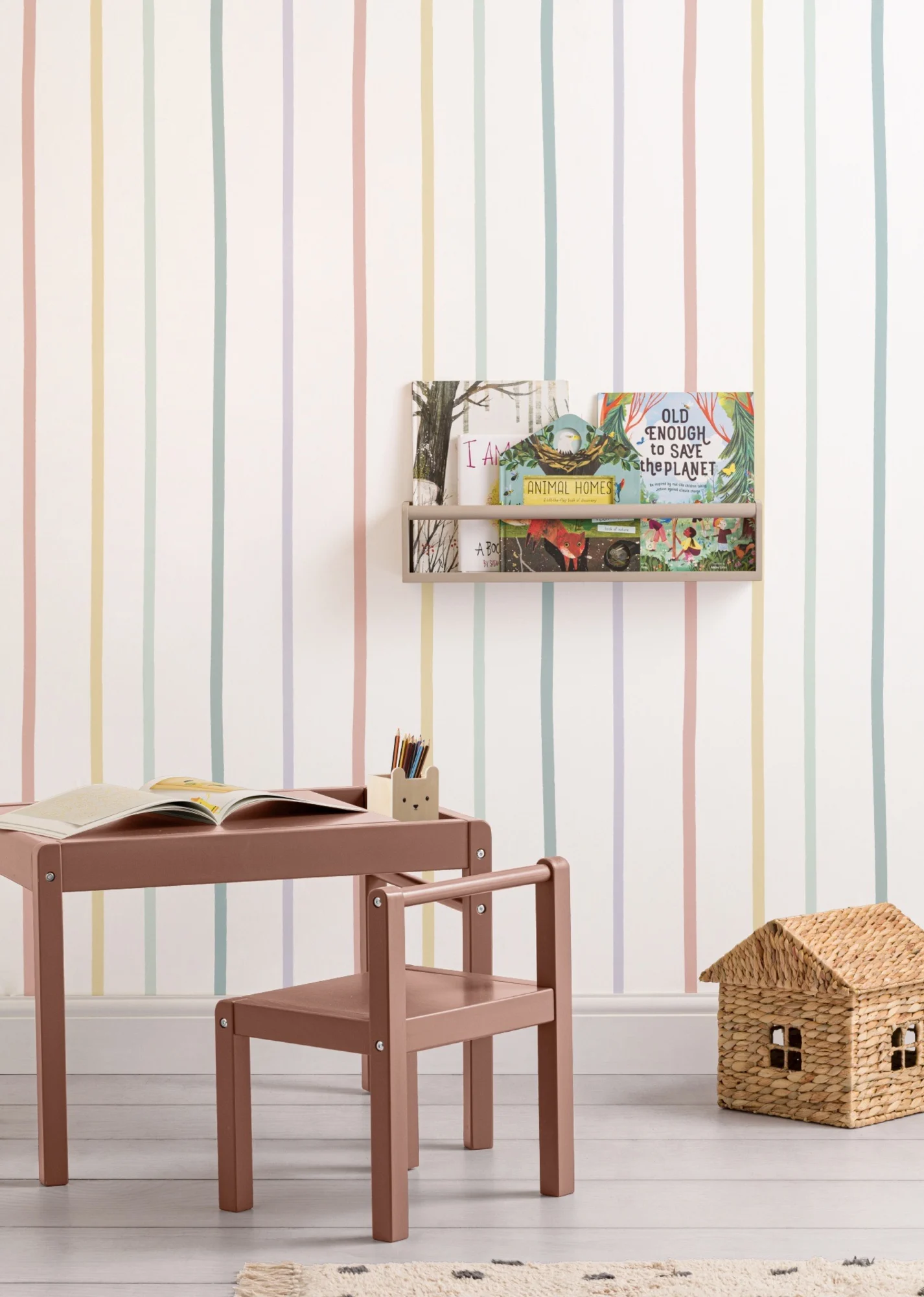 A vibrant kids’ room with multicolor striped wallpaper, a book shelf, and a small study table.