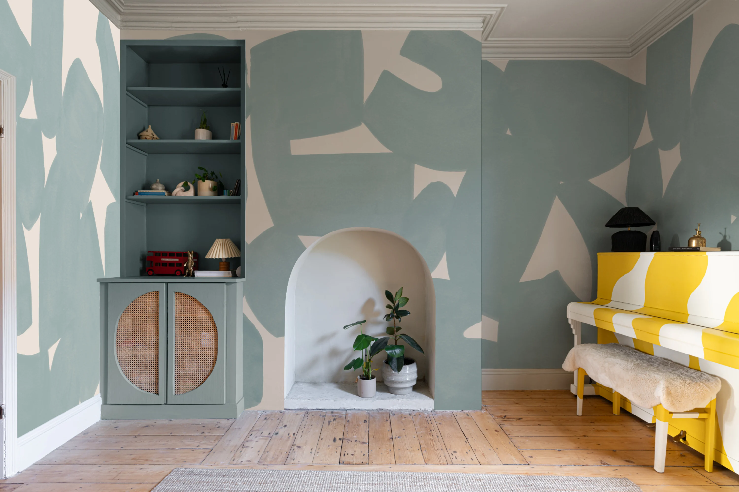 Living room with abstract blue and cream mural, built-in shelving, and yellow striped piano.