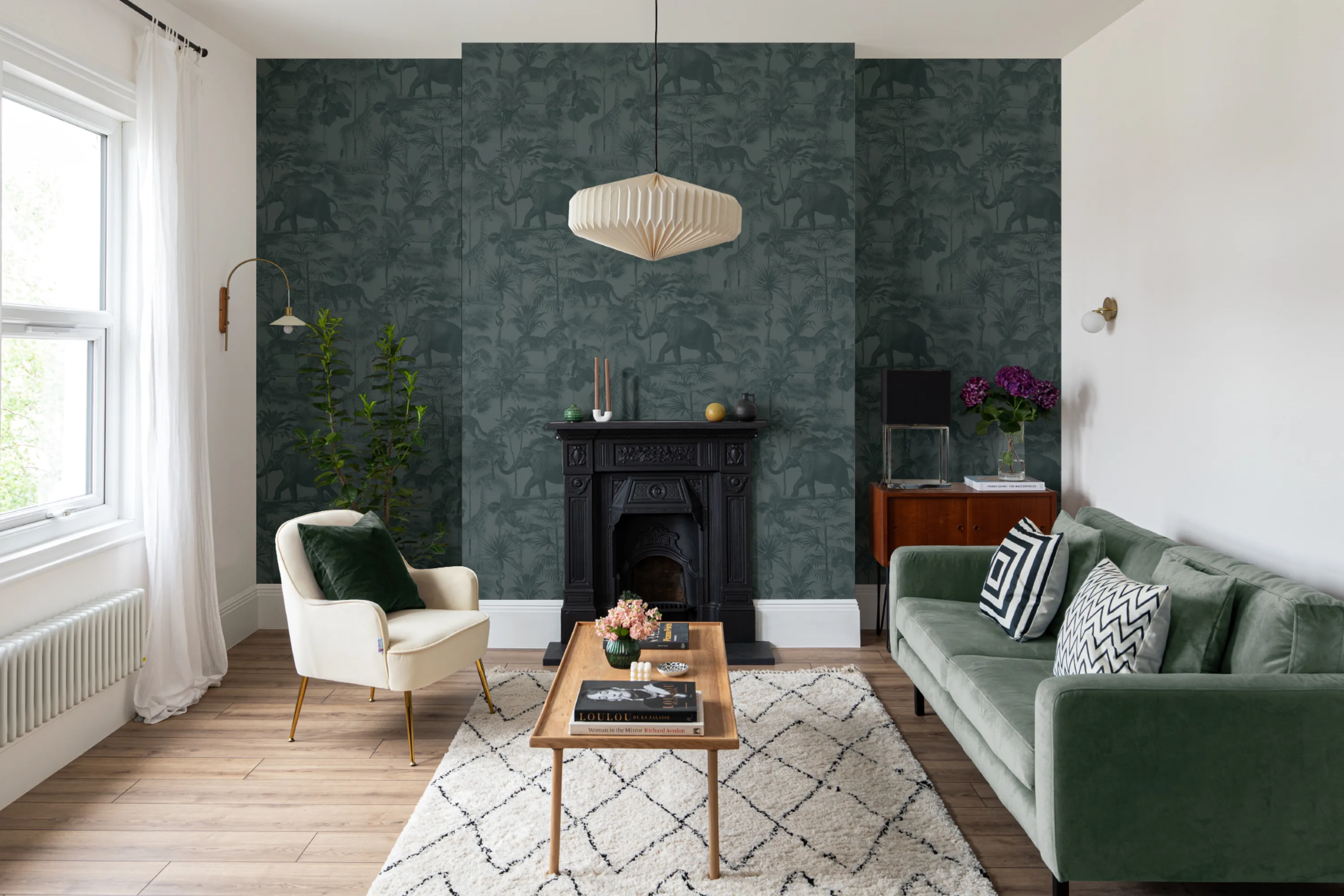 A sophisticated living room with a dark green tropical mural behind a black fireplace.