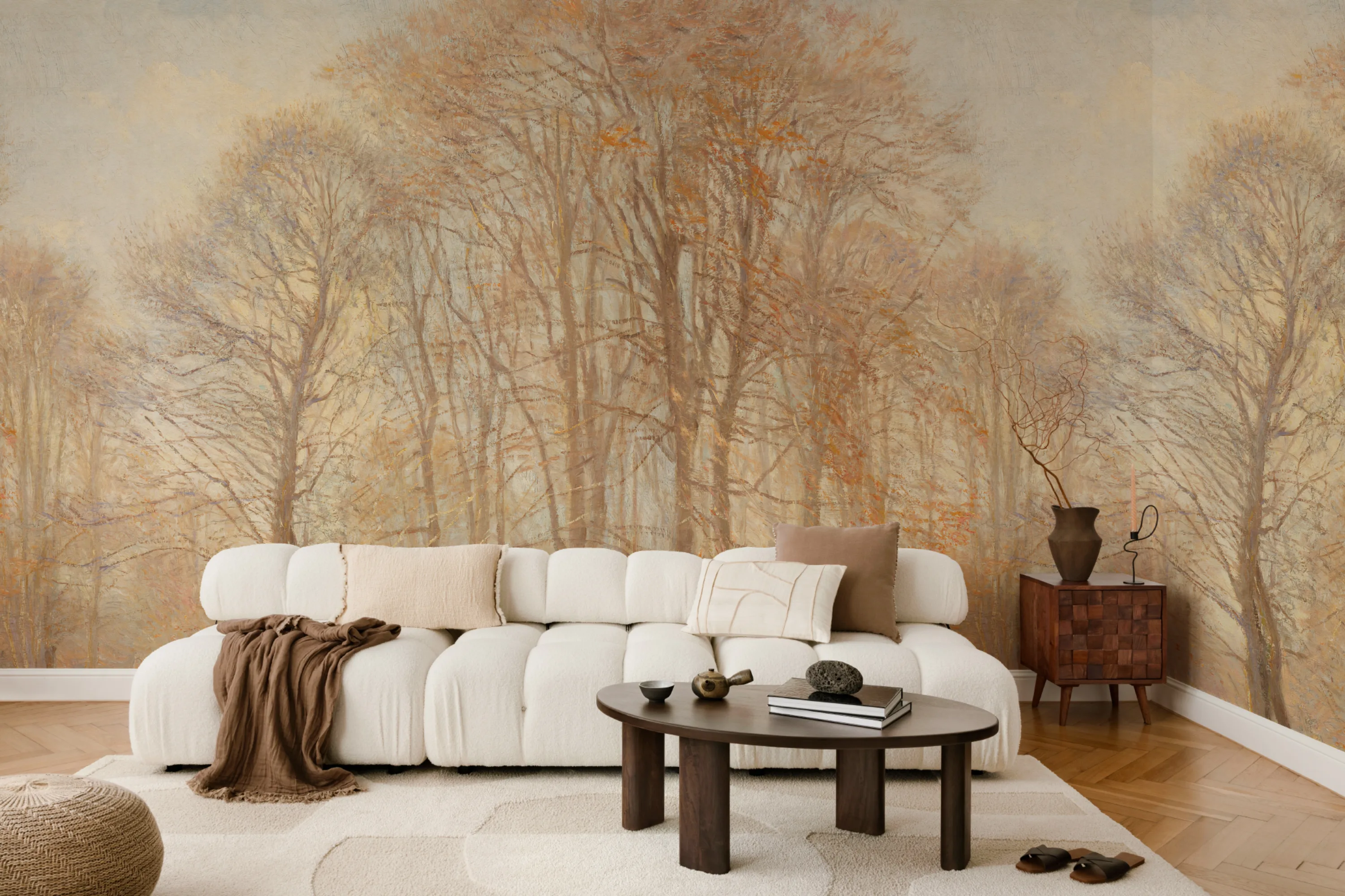 Living room with a cream sofa and textured rug against a scenic mural of leafless trees in soft autumn tones.