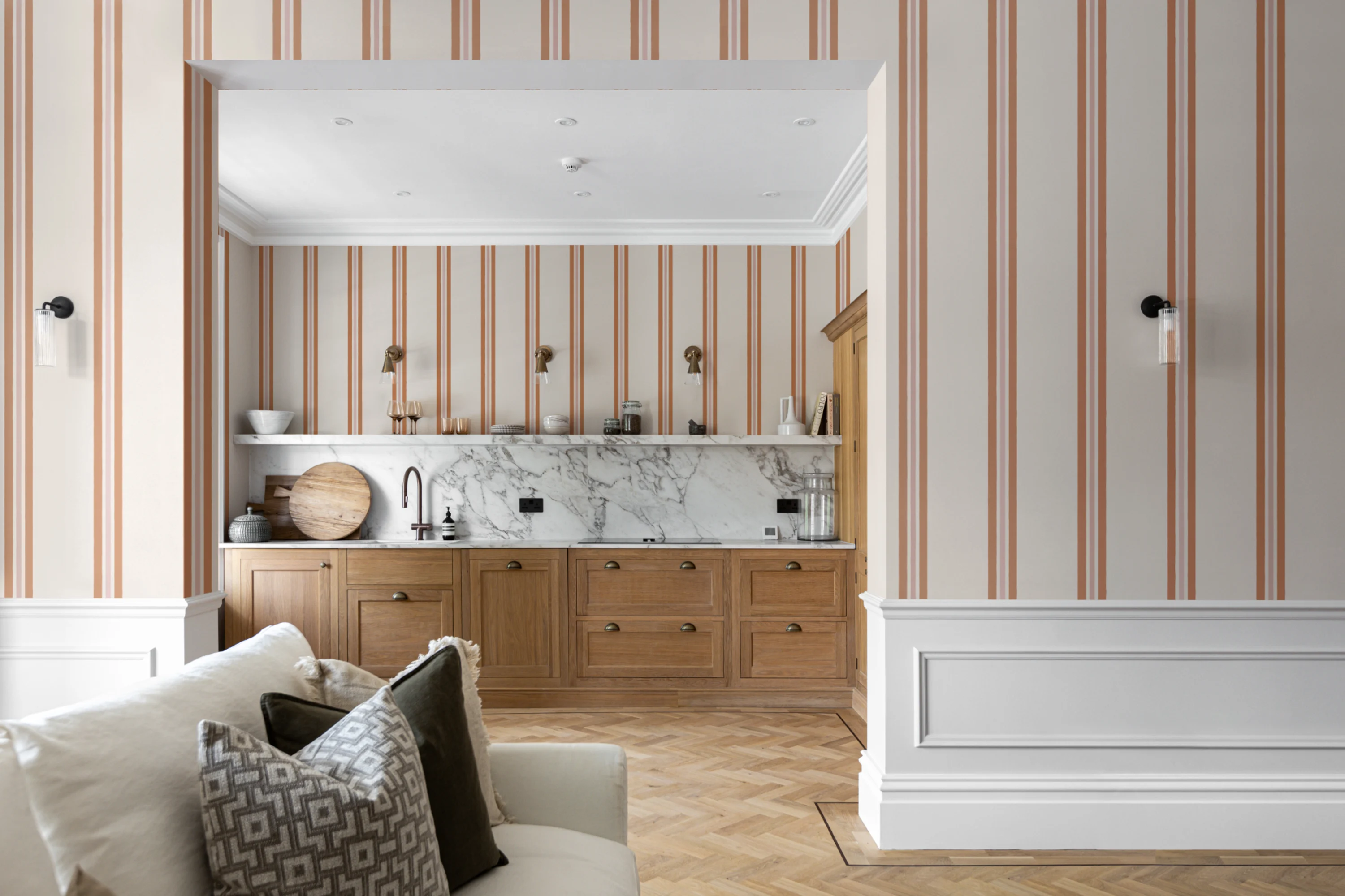 Elegant open kitchen and living area with vertical terracotta and cream striped wallpaper and wood cabinetry.