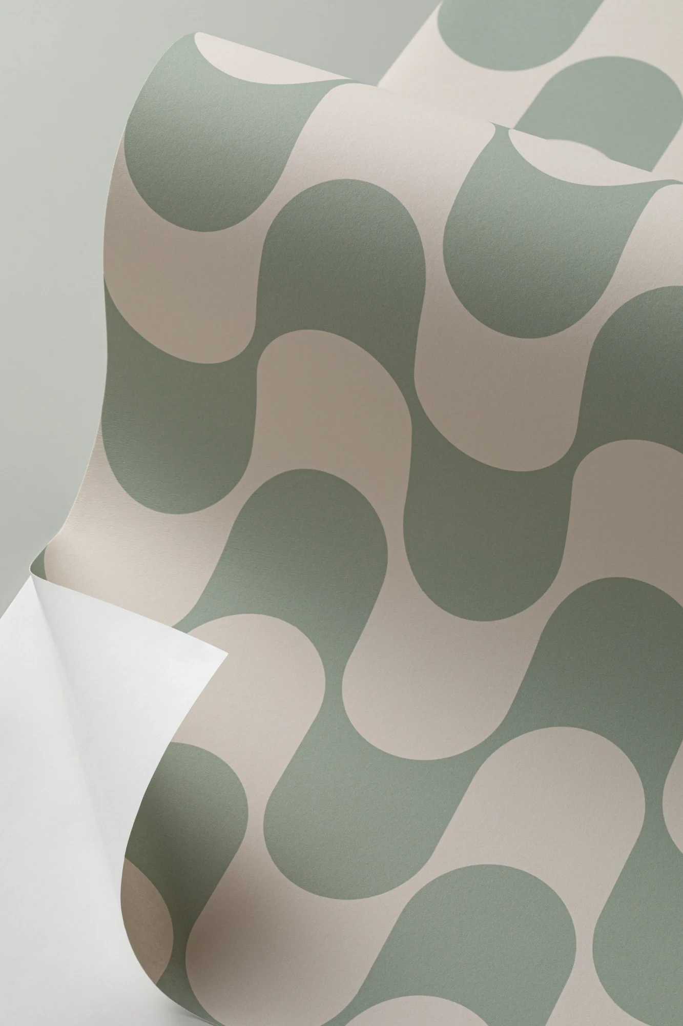 A close-up of retro-style peel-and-stick wallpaper with green and cream wavy shapes being peeled back.