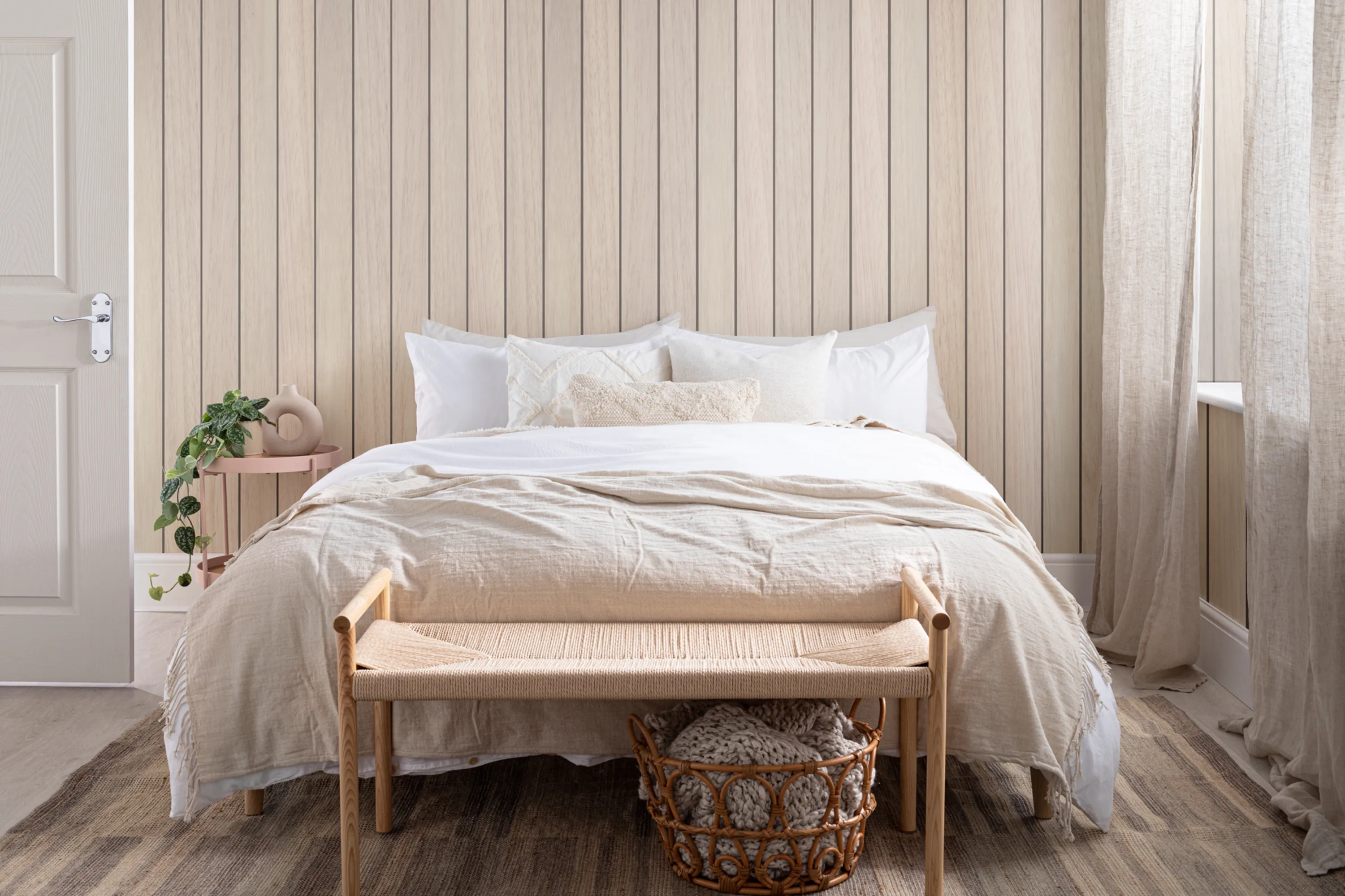 Neutral bedroom with a light wood panel-effect wallpaper, natural linen bedding, and soft woven accessories.