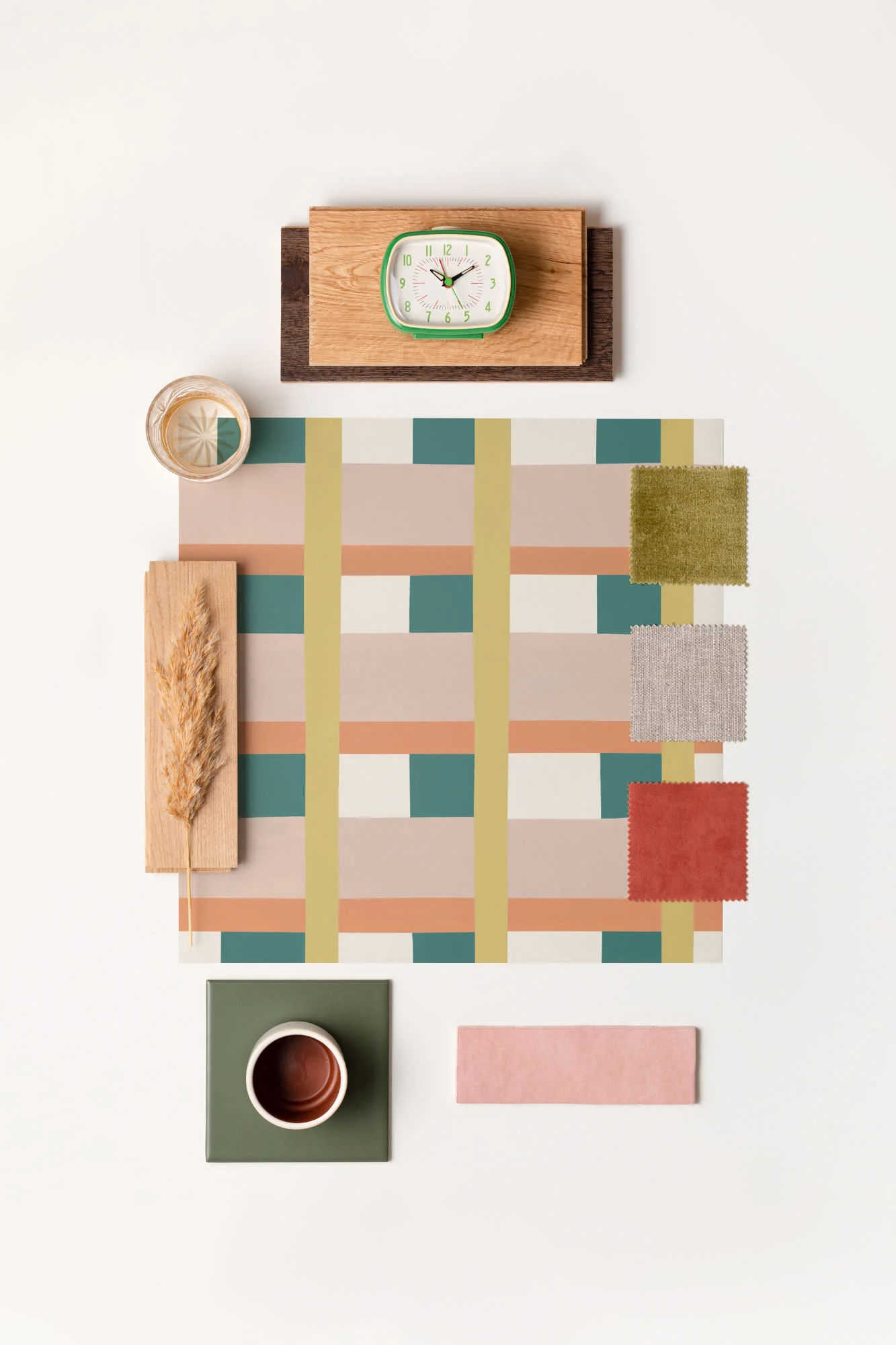 A flatlay of a bold check wallpaper sample surrounded by fabric swatches, wood samples, and a clock.