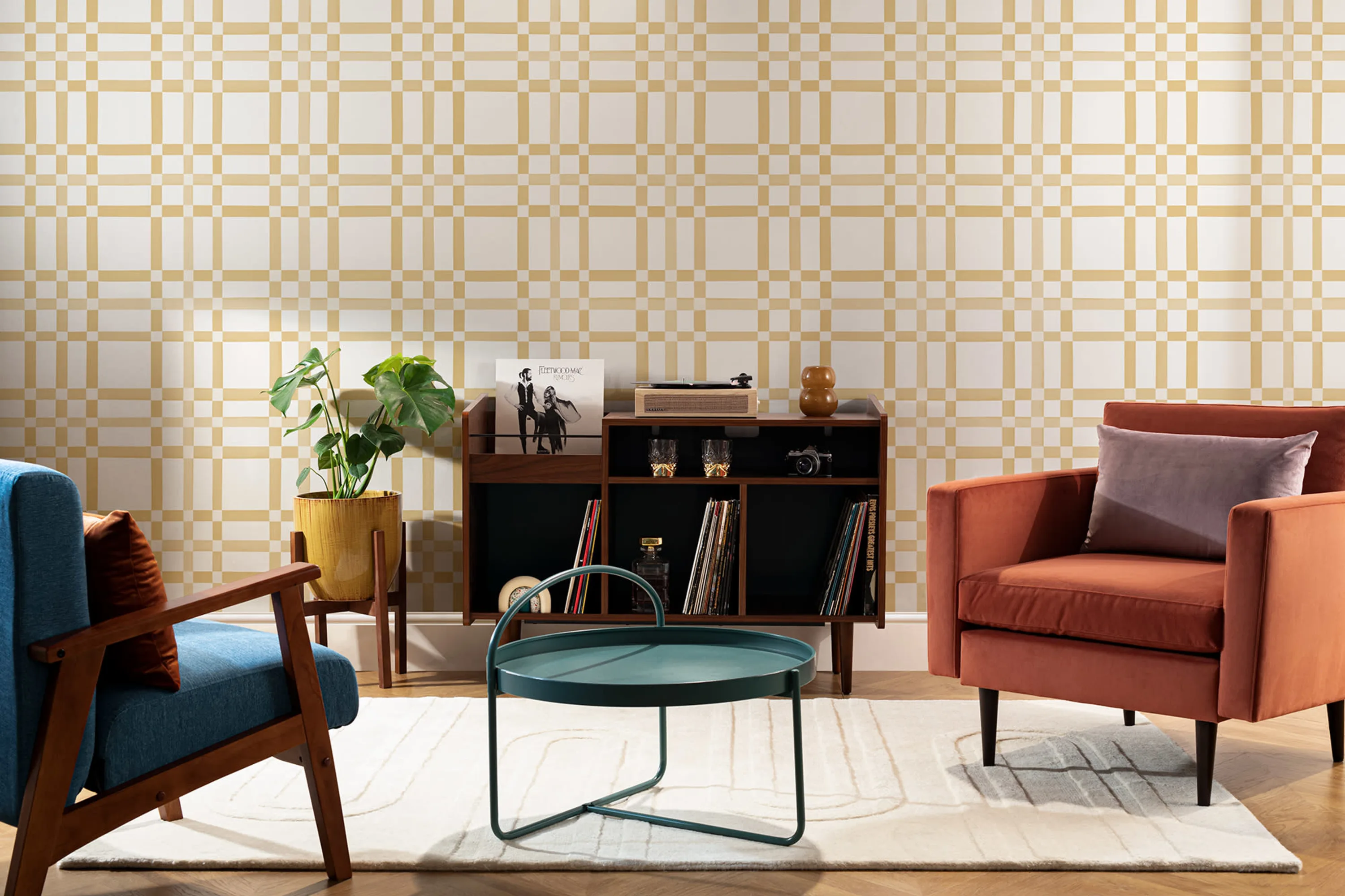 A yellow plaid wallpaper complements retro furniture, including a rust armchair and wood shelving.