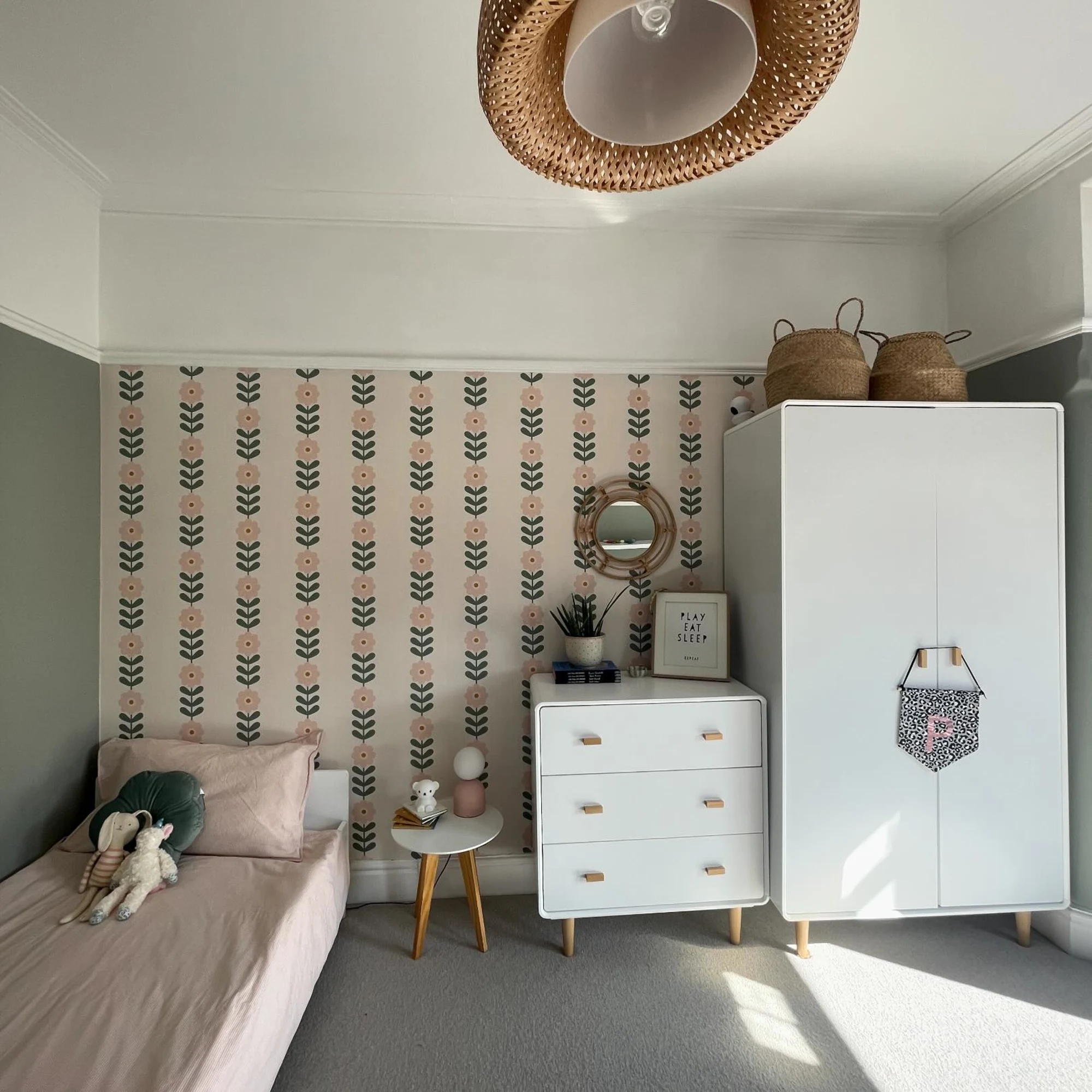 Kids’ bedroom with floral wallpaper accent wall, white furniture, and natural decor accents.