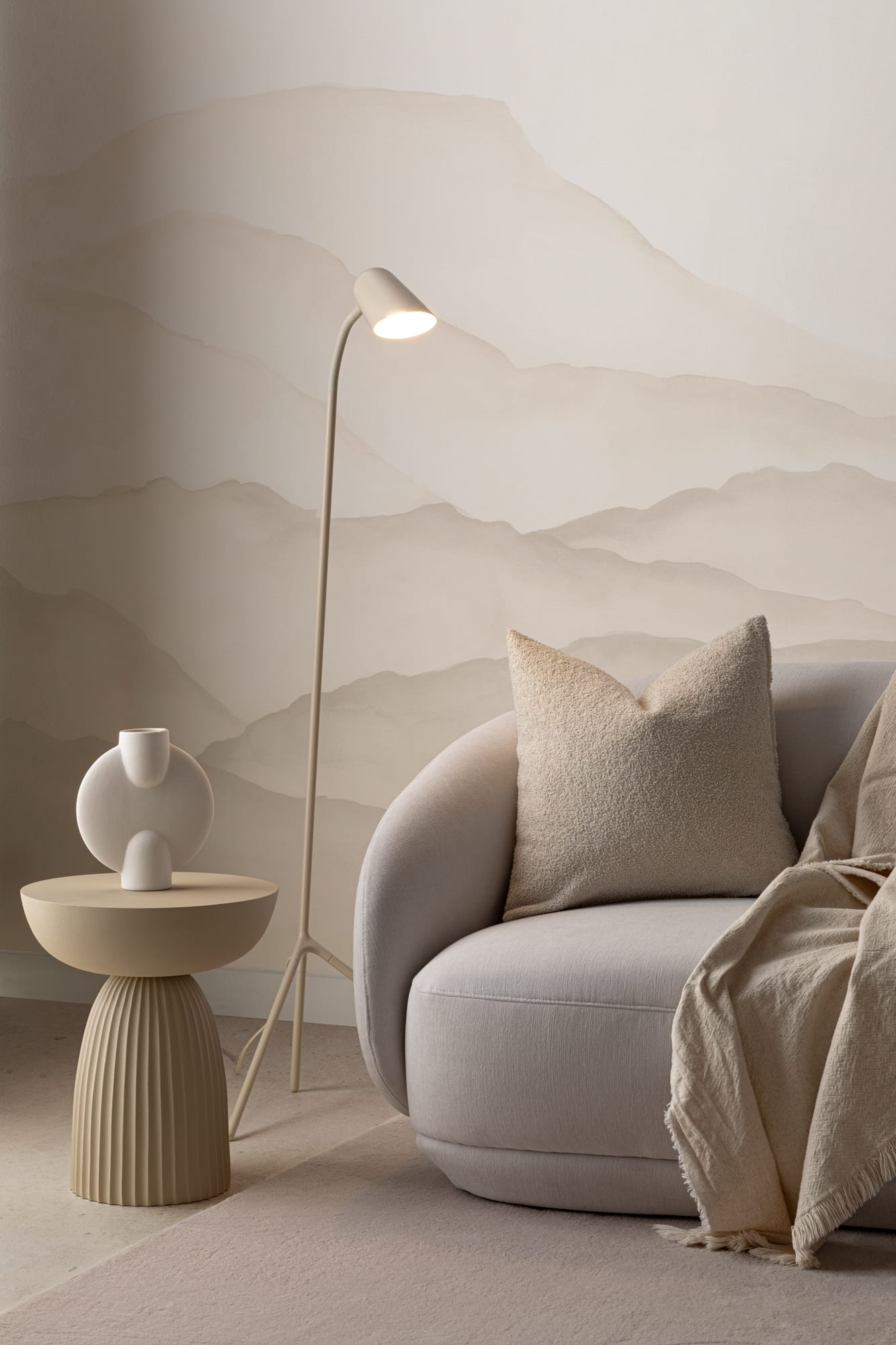 Serene living room with neutral mountain-inspired watercolor mural and a cozy armchair with throw blanket.