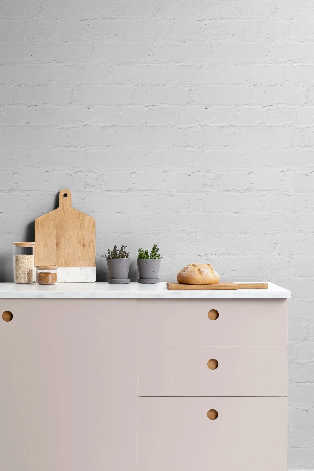 A matte light gray brick wallpaper used as a kitchen backsplash behind a modern countertop with kitchen essentials.