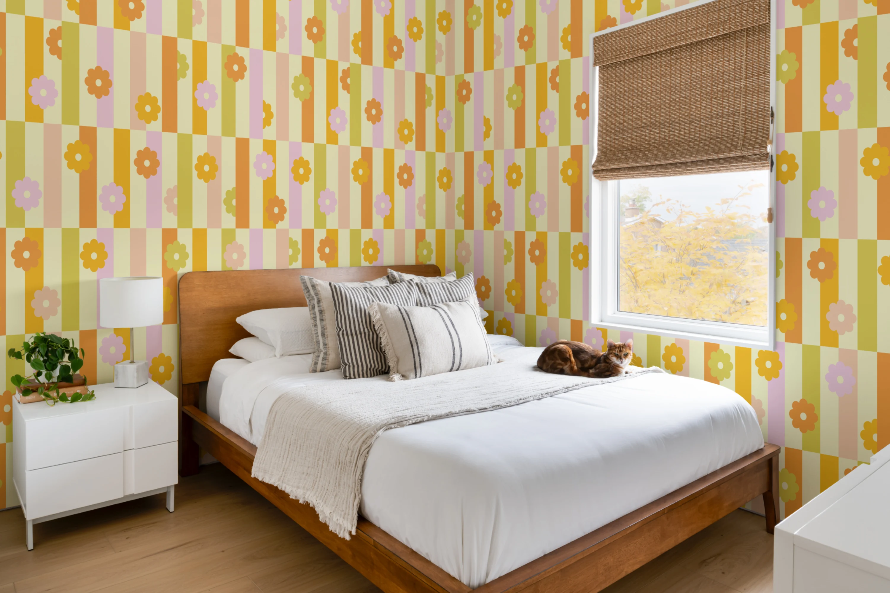 Bedroom with yellow, pink, and orange striped wallpaper decorated with simple flower motifs.