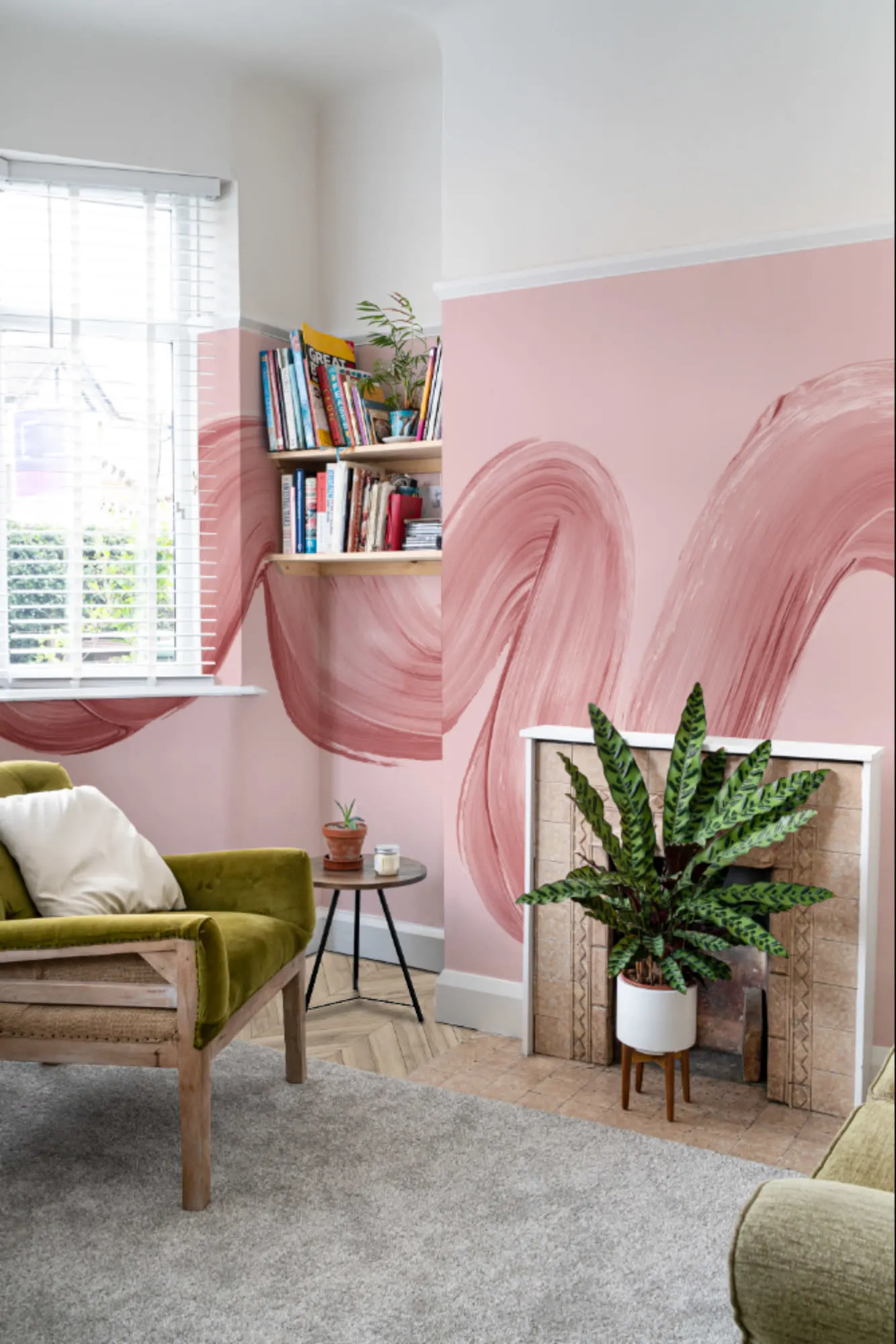 A pink living room features a bold brushstroke mural wrapping around the chimney breast and corner wall.
