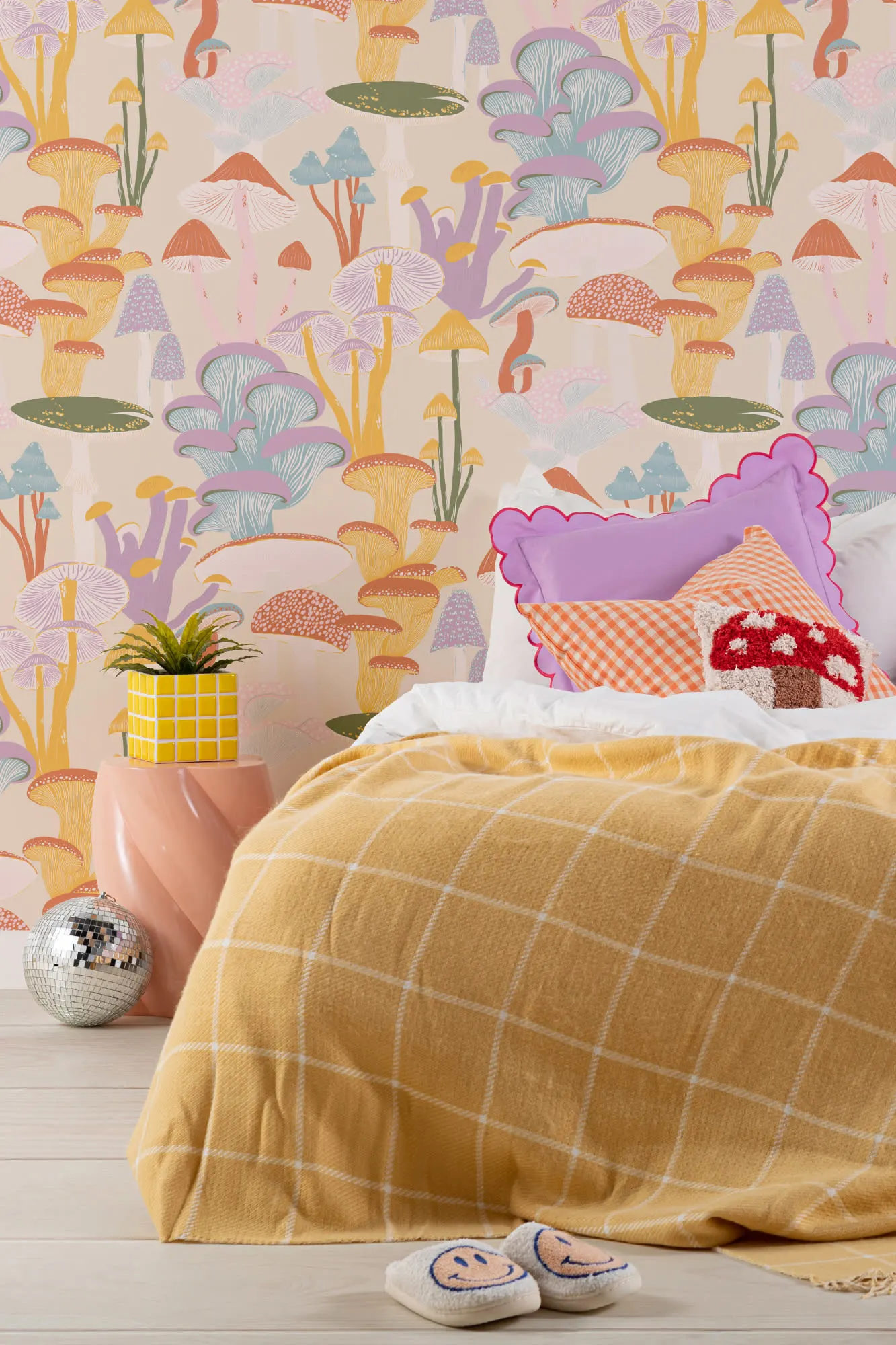 Bedroom with colorful mushroom wallpaper, gingham pillows, yellow checkered blanket, and playful decor.