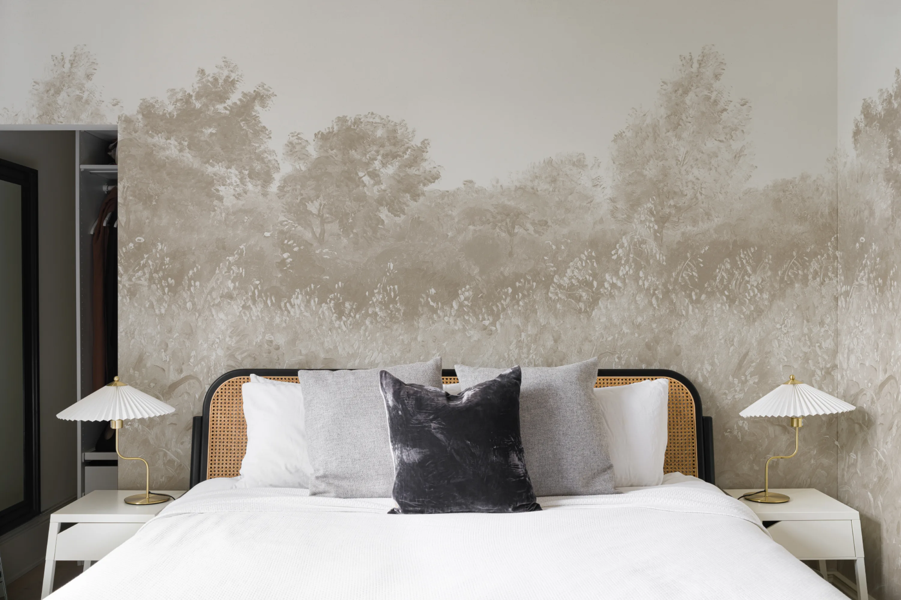 Neutral bedroom with a sepia-toned forest mural behind a cane bed and minimalist nightstands