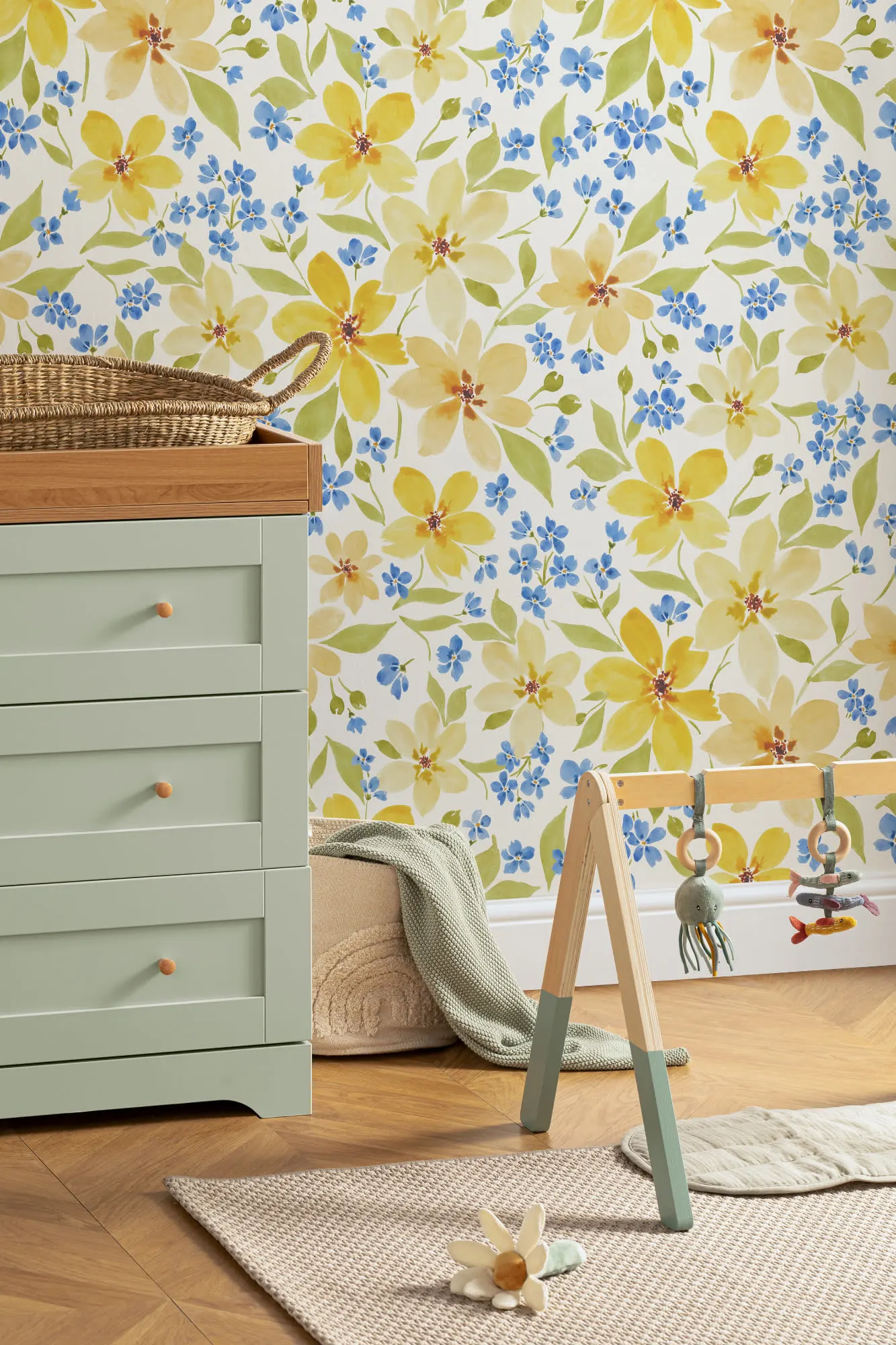 Yellow and blue floral wallpaper in a nursery with mint green drawers and wooden toys.