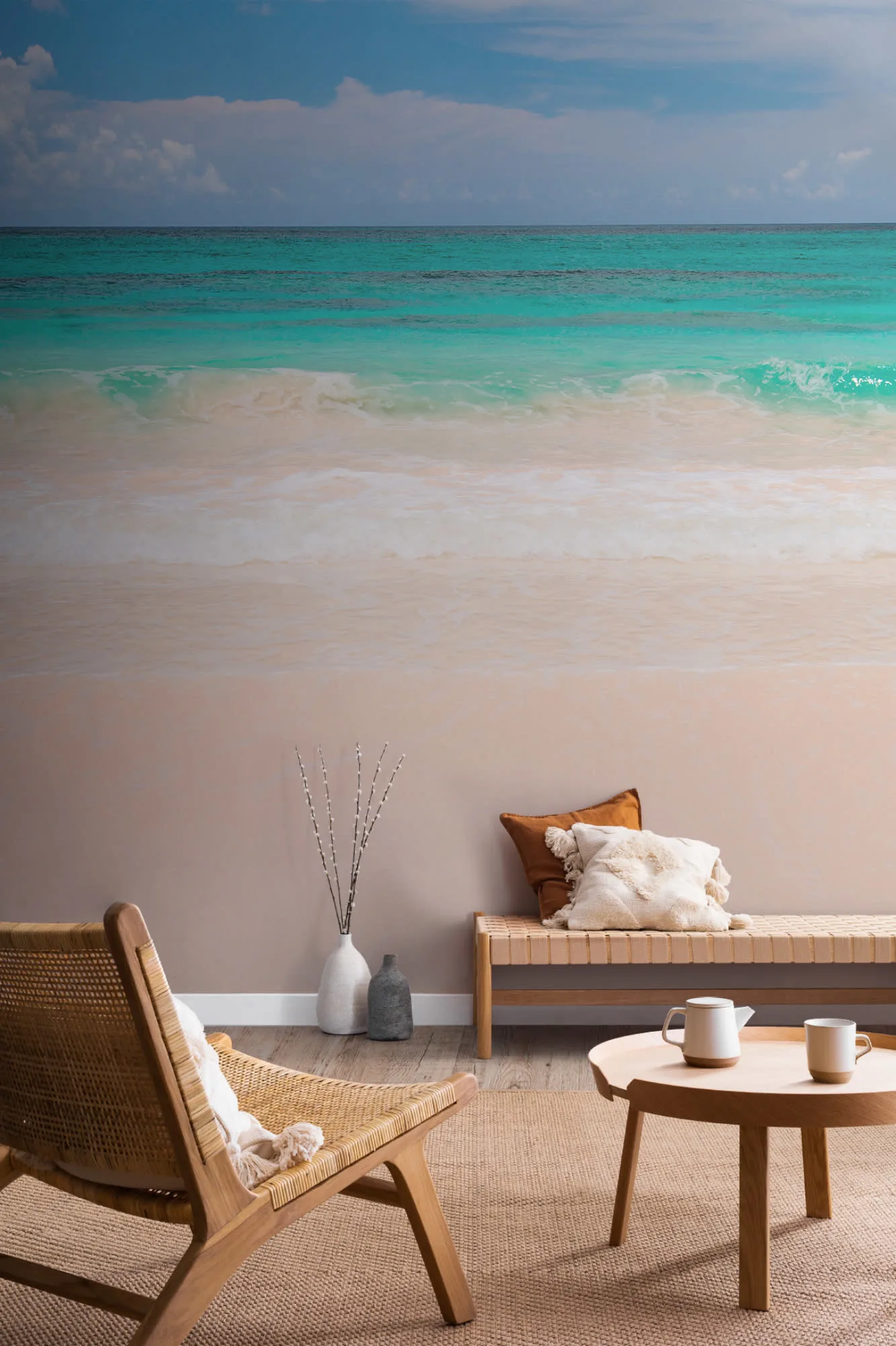 Beach mural with turquoise ocean waves and sandy shore behind coastal-style furniture.