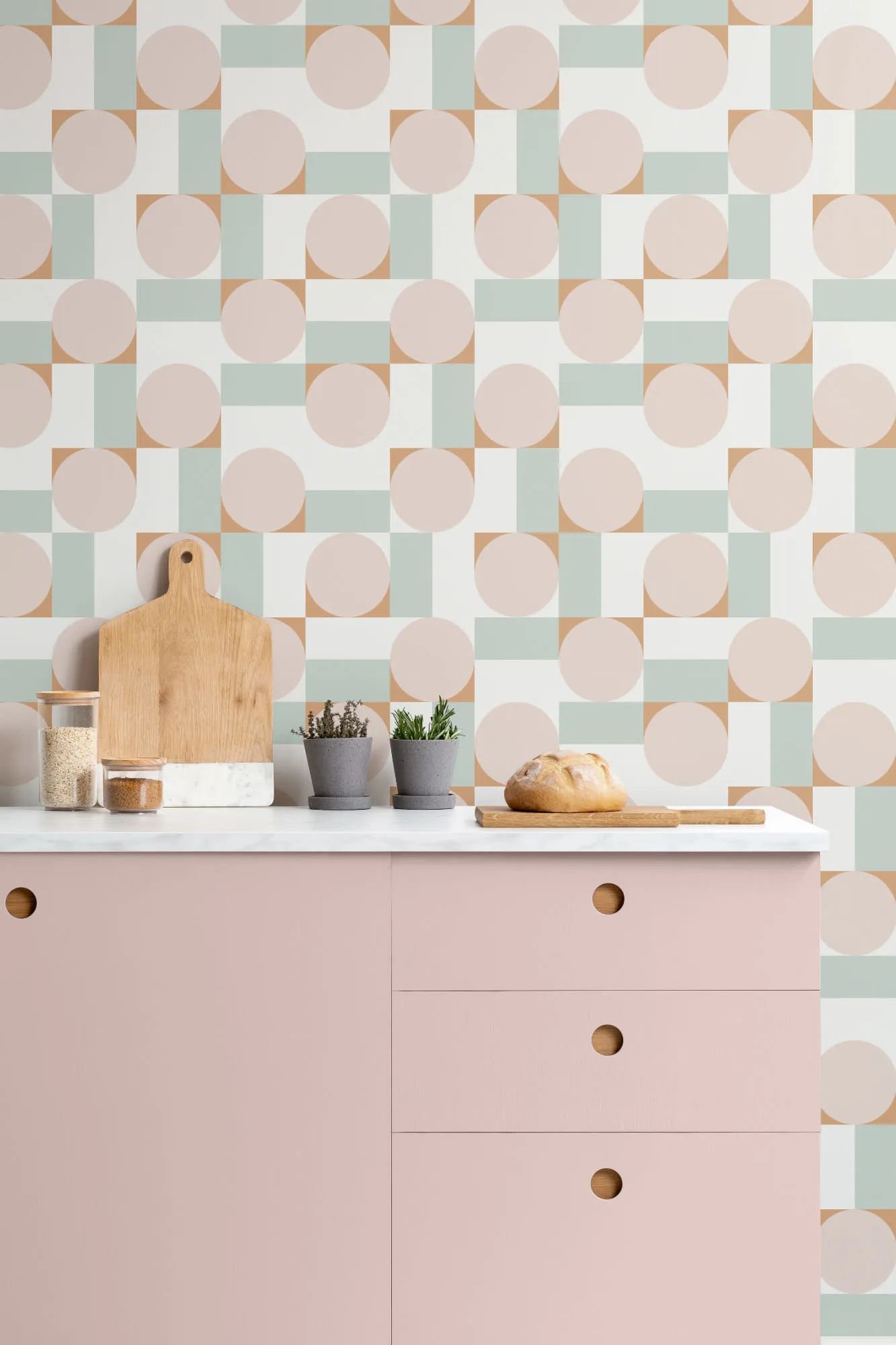 Retro-style kitchen with geometric wallpaper in pastel tones and blush pink cabinetry.