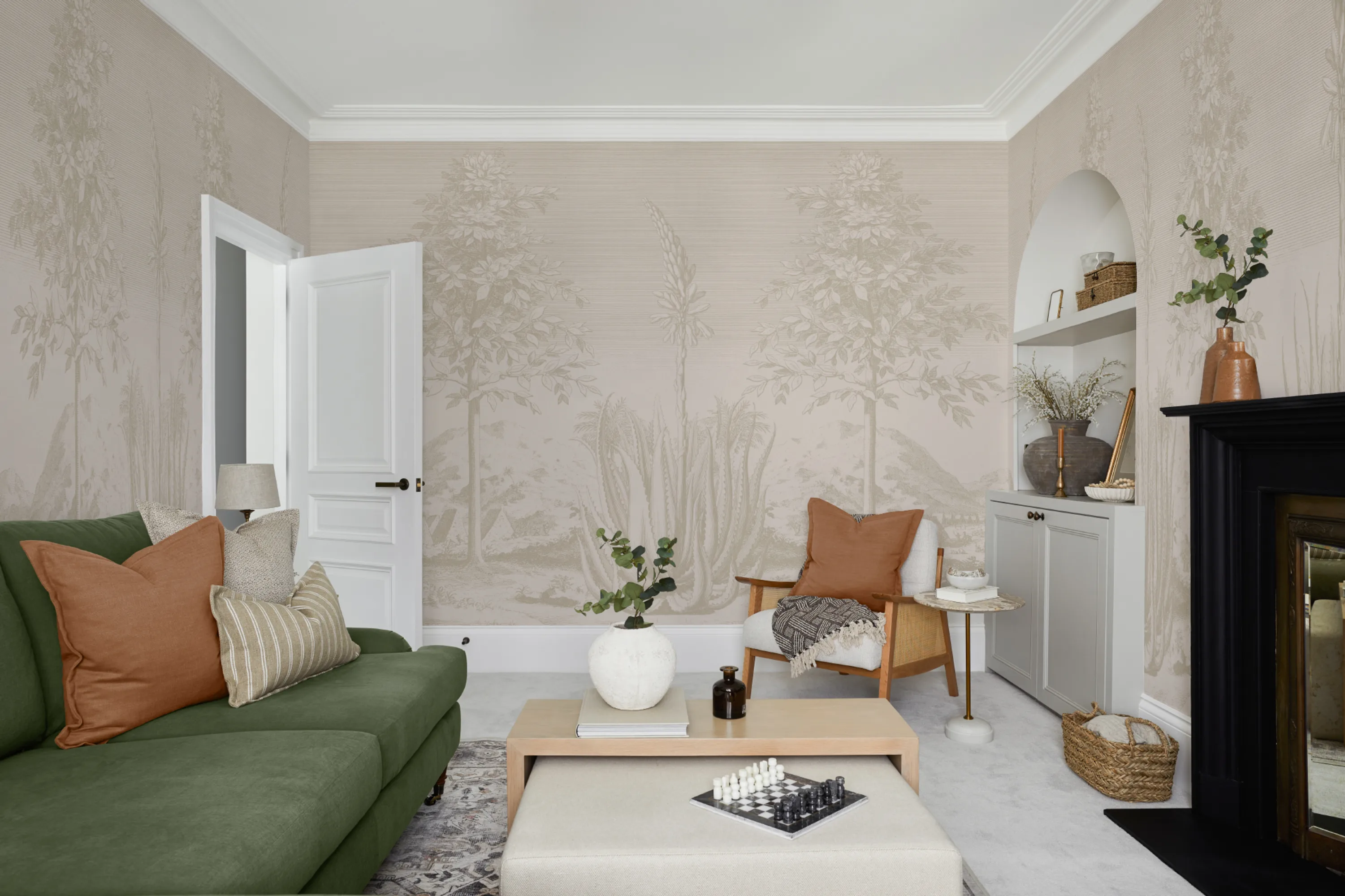 A neutral botanical mural complements earthy-toned decor and a green sofa in a cozy living room
