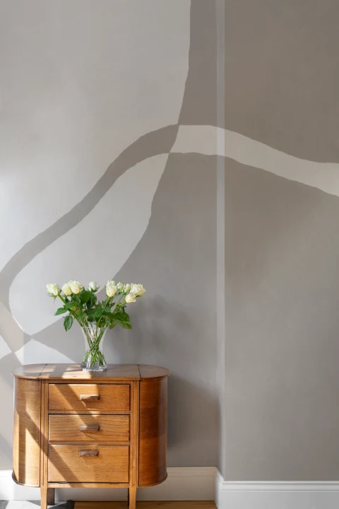 Mural de formas curvas pintado a mano en beige suave con textura de yeso